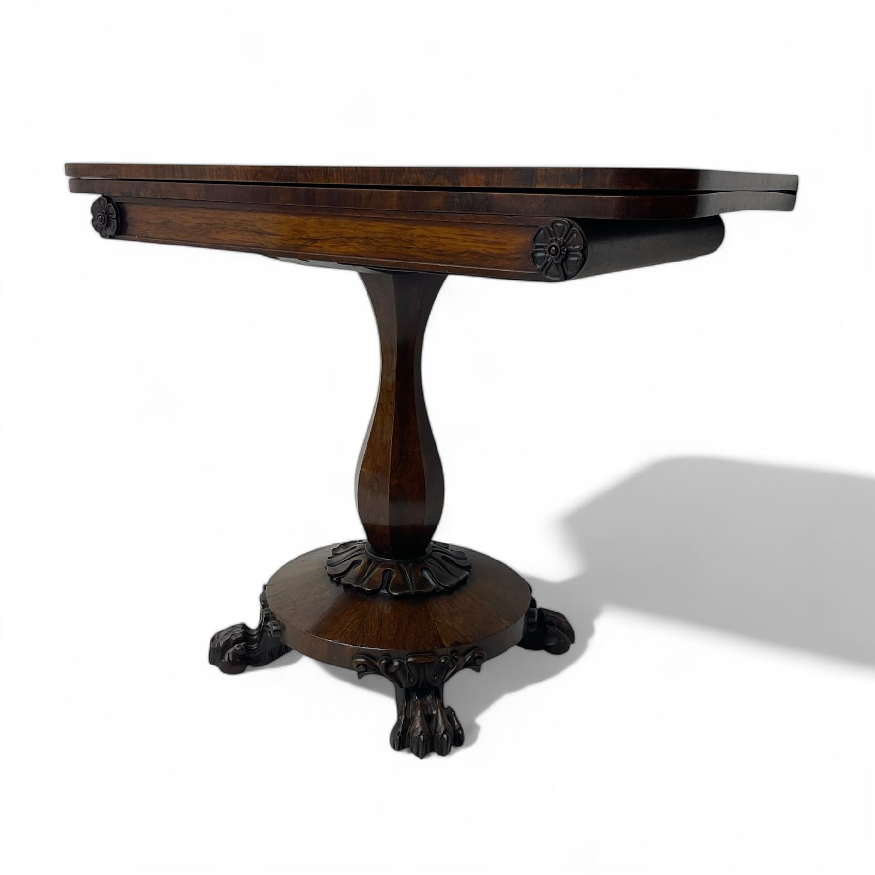 Victorian mahogany tea table, rectangular top with rounded corners, folding and swivelling to reveal interior surface, supported on a faceted baluster-shaped column, raised on a circular platform base with carved acanthus details, ending in four lion paw feet