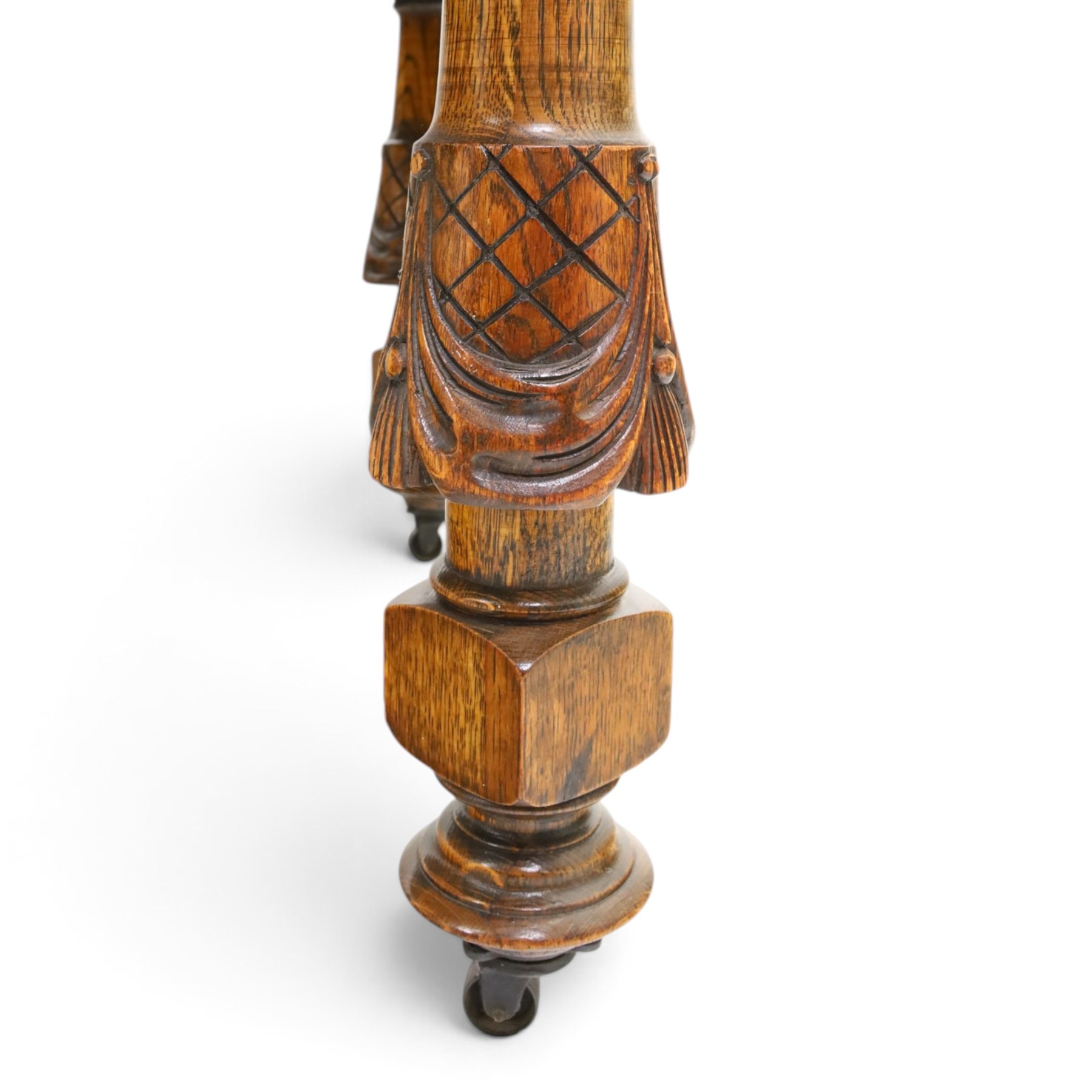 Late 19th century French oak extending dining table, oval top with moulded edge and plain frieze, raised on four ornate carved supports decorate with carved latticework and large festoons with tassels, on turned feet, with two additional leaves