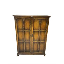 Early to mid-20th century oak double wardrobe, projecting cornice over two panelled doors with Corinthian column decoration, on pad feet