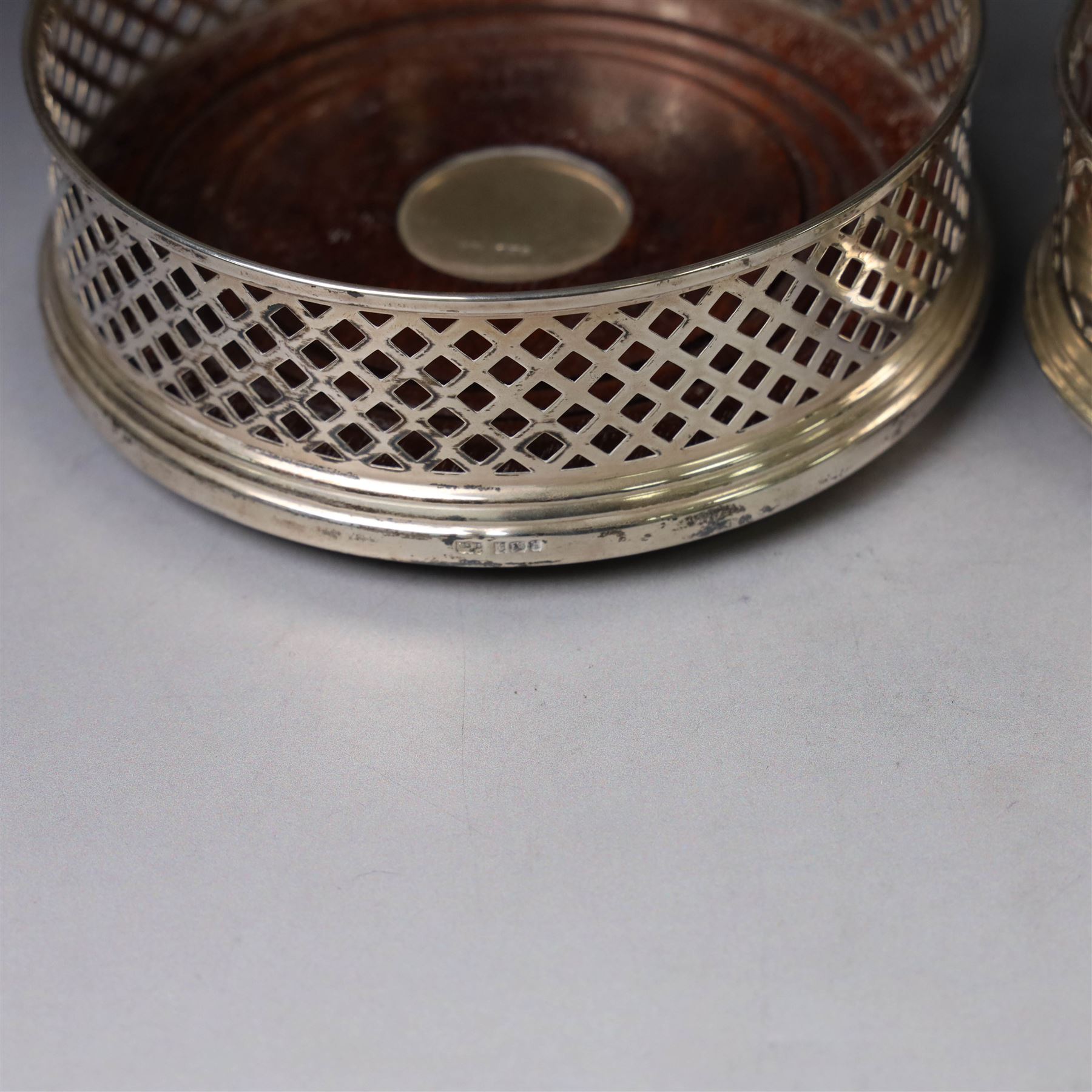 Two silver mounted bottle coasters, the larger example with latticework sides, hallmarked Mappin & Webb Ltd, Birmingham 1993, the smaller example with pierced sides, hallmarked W I Broadway & Co, Birmingham 1998, largest D12cm