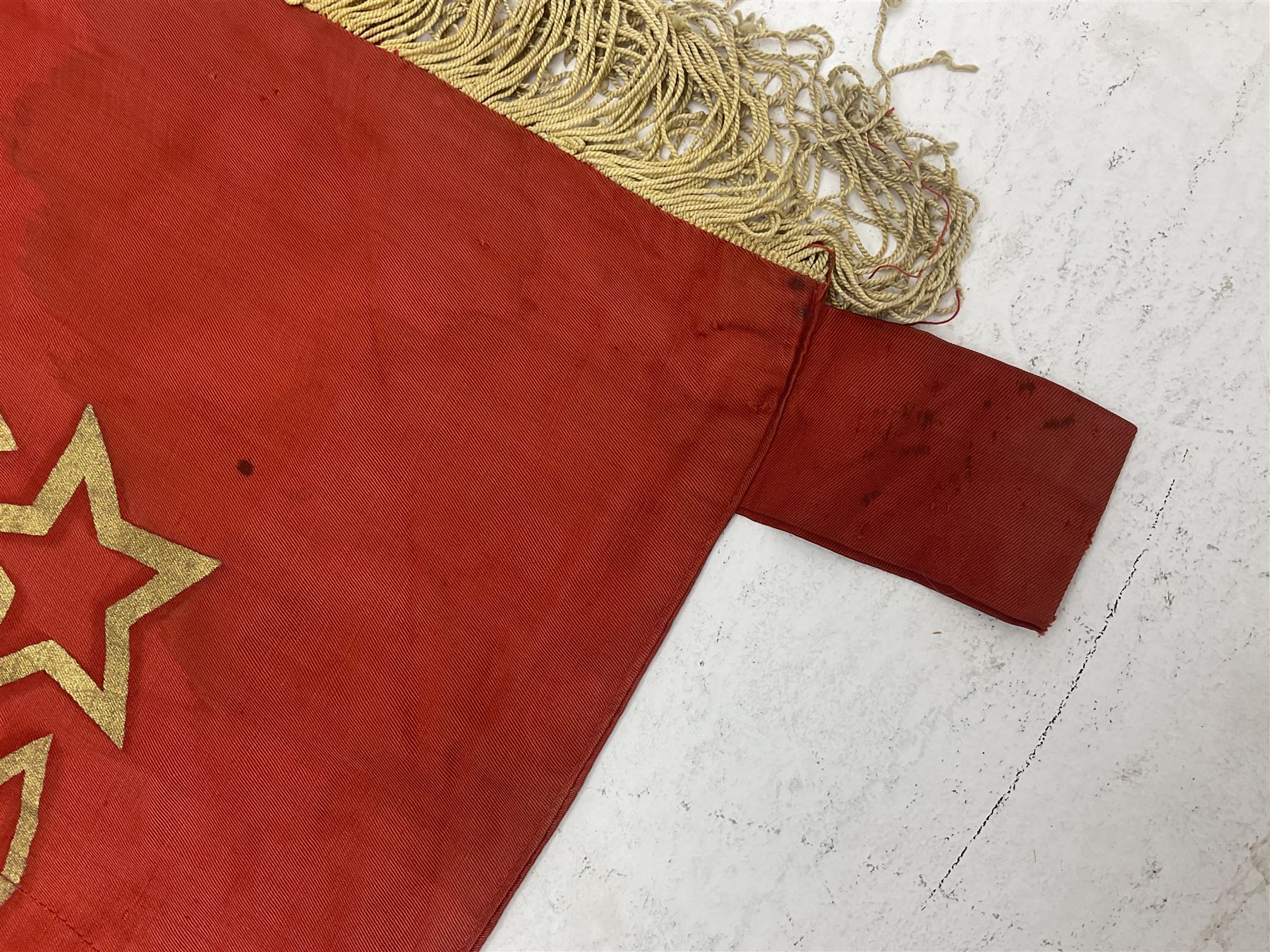 1970s Soviet banner printed in gold on a red ground, roughly translates as 'Transferable Banner - To the winner in the Socialist Competition' and 'Work Study Live by Communism' verso; wreath of wheat ears to either side; tassels on three sides 110 x 155cm