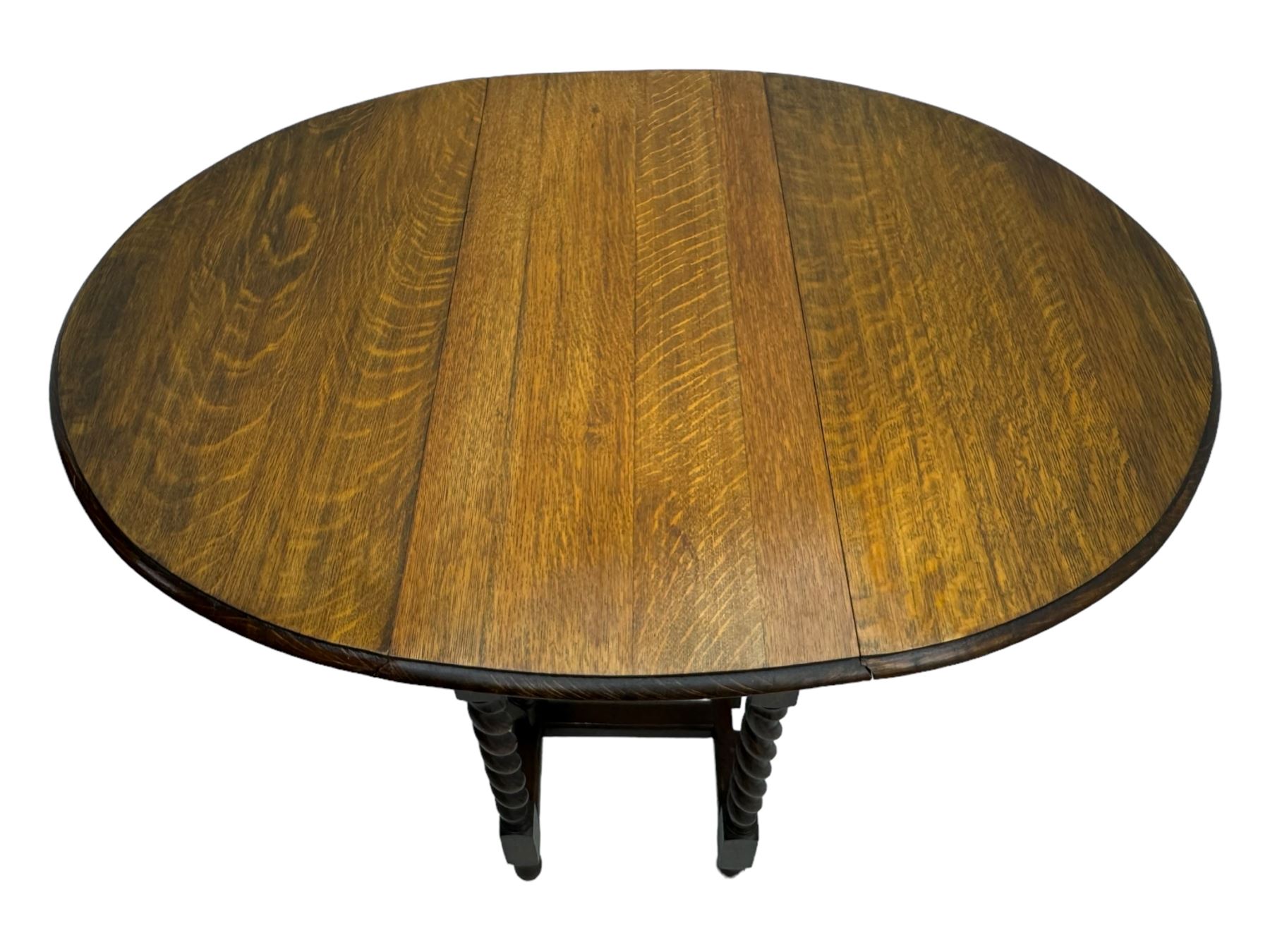 Early 20th century oak gateleg table, oval top with drop leaves supported by barley twist swing supports, united by plain stretchers, on turned feet (W119cm, D92cm, H77cm);