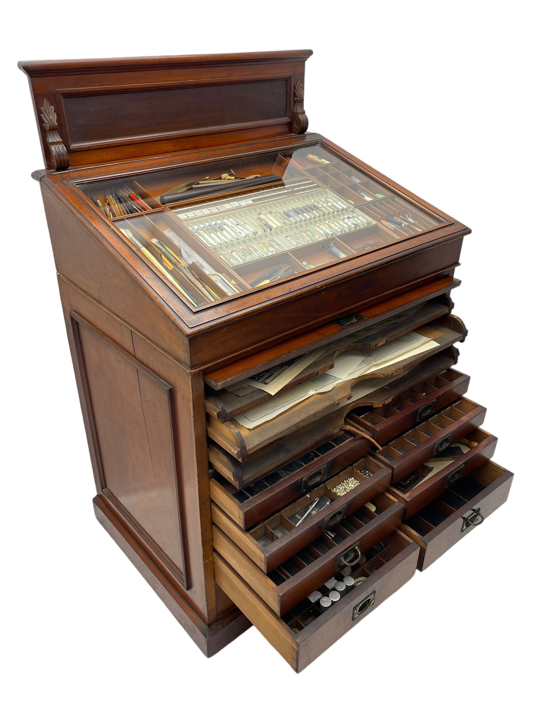 Edwardian mahogany artist's cabinet once belonging to the British artist Eli Marsden Wilson (1877-1965), raised panelled back mounted by carved brackets, sloped and hinged glazed lid enclosing paint holders and compartments, up-and-over panelled door revealing three slides, fitted with two banks of five graduating drawers with recessed brass handles, on skirted base.

Together with a quantity of artists' equipment and tools including paints, paintbrushes, charcoal, chalks, etc. and various prints relating to the life of the artist, including Quaker anti-war posters, Victorian Stevengraphs, and various chromolithographs 

Provenance: Removed from the studio of Eli Marsden Wilson. The cabinet comes to us for sale through family descent. The vendor is descendant of Marsden. Many further etchings removed from the cabinet are being sold in the Spring Art Sale, Friday 15th March 2024, Lots 265-271.

Notes: born in Ossett, Eli Marsden Wilson was the only son of Alfred Wilson, a foreman beamer, and Emma Marsden, and had five sisters. After studying at Wakefield College of Art, he moved to the Royal College of Art in London, where he became a pupil of Sir Frank Short. He had his first exhibit at the Royal Academy in 1905, the same year he married fellow artist Hilda Mary Pemberton.

A Quaker, vegetarian, and pacifist, he was a conscientious objector in World War I and as such was imprisoned in 1917 for two years. In September 1922 he was commissioned by Princess Marie Louise to produce miniature etchings for Queen Mary's Dolls' House at Windsor Castle; two such etchings are being sold in the Spring Art Sale, Friday 15th March 2024, Lot 265.