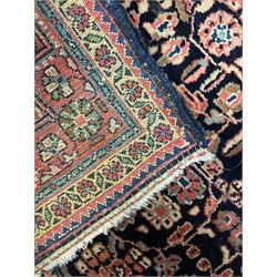 Persian indigo ground rug, the field decorated with intricate interlaced foliage branches and small flower heads, shaped floral design central medallion, the border decorated with scrolling branch and flower heads within guard bands 
