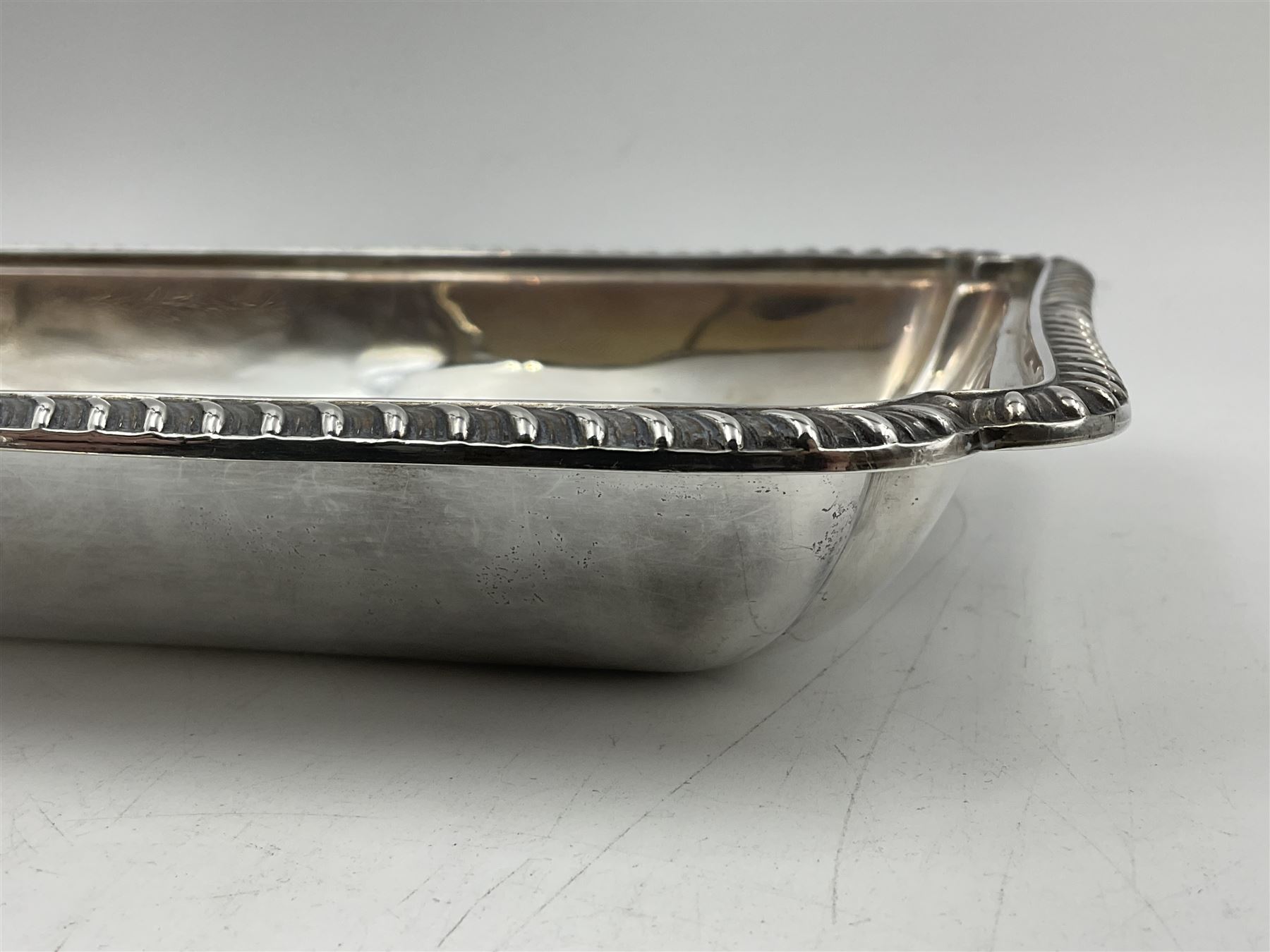Early 20th century silver entree dish and cover, of rectangular form with shaped corners and oblique gadrooned borders to base and cover, the cover with loop 'bamboo' handle, hallmarked Thomas Bradbury & Sons Ltd, Sheffield 1930, including handle H10.5cm L24.5cm