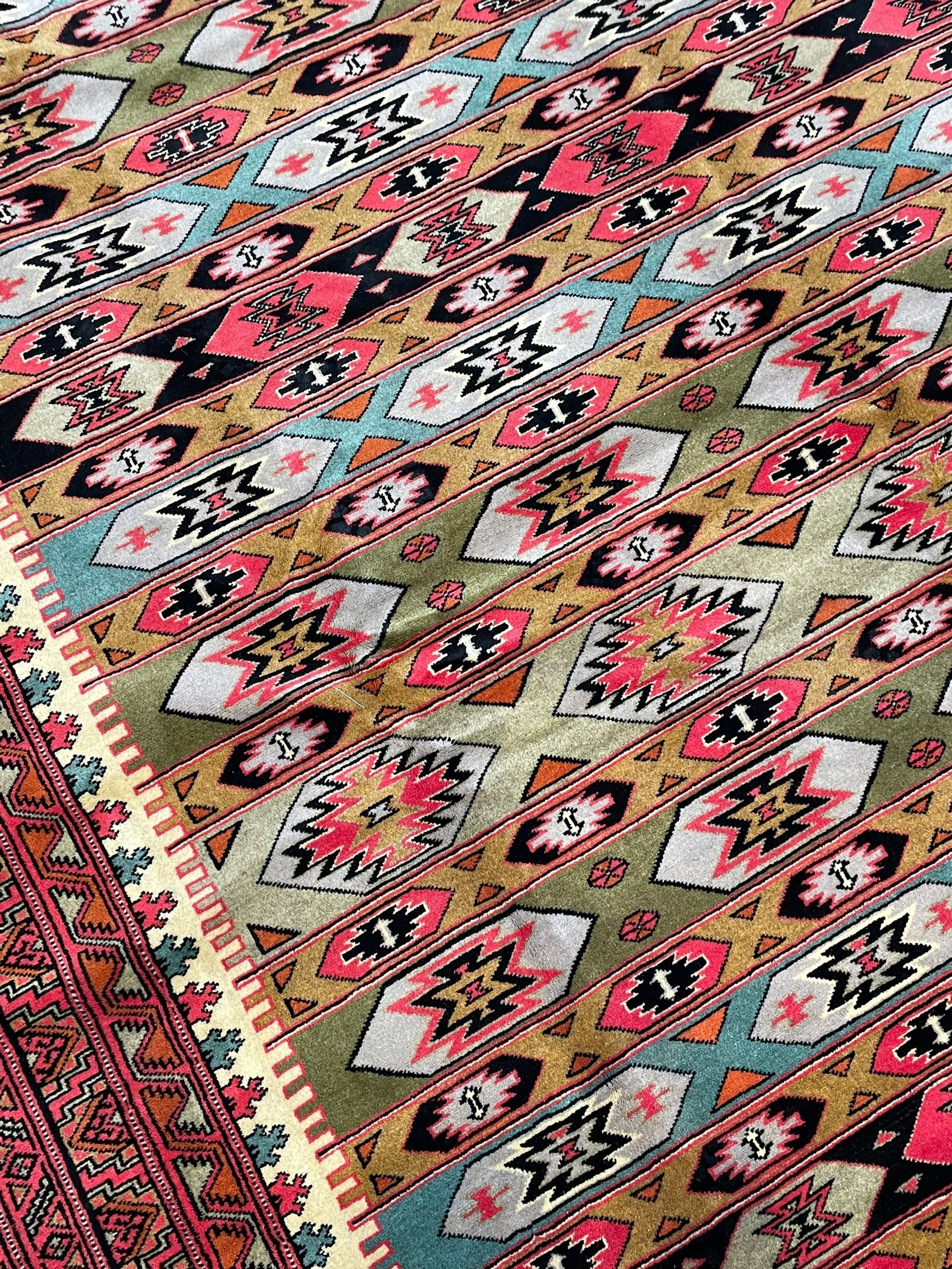 Turkaman red ground rug, the field divided into horizontal rows and decorated with geometric motifs, intricately pattern borders and end panels