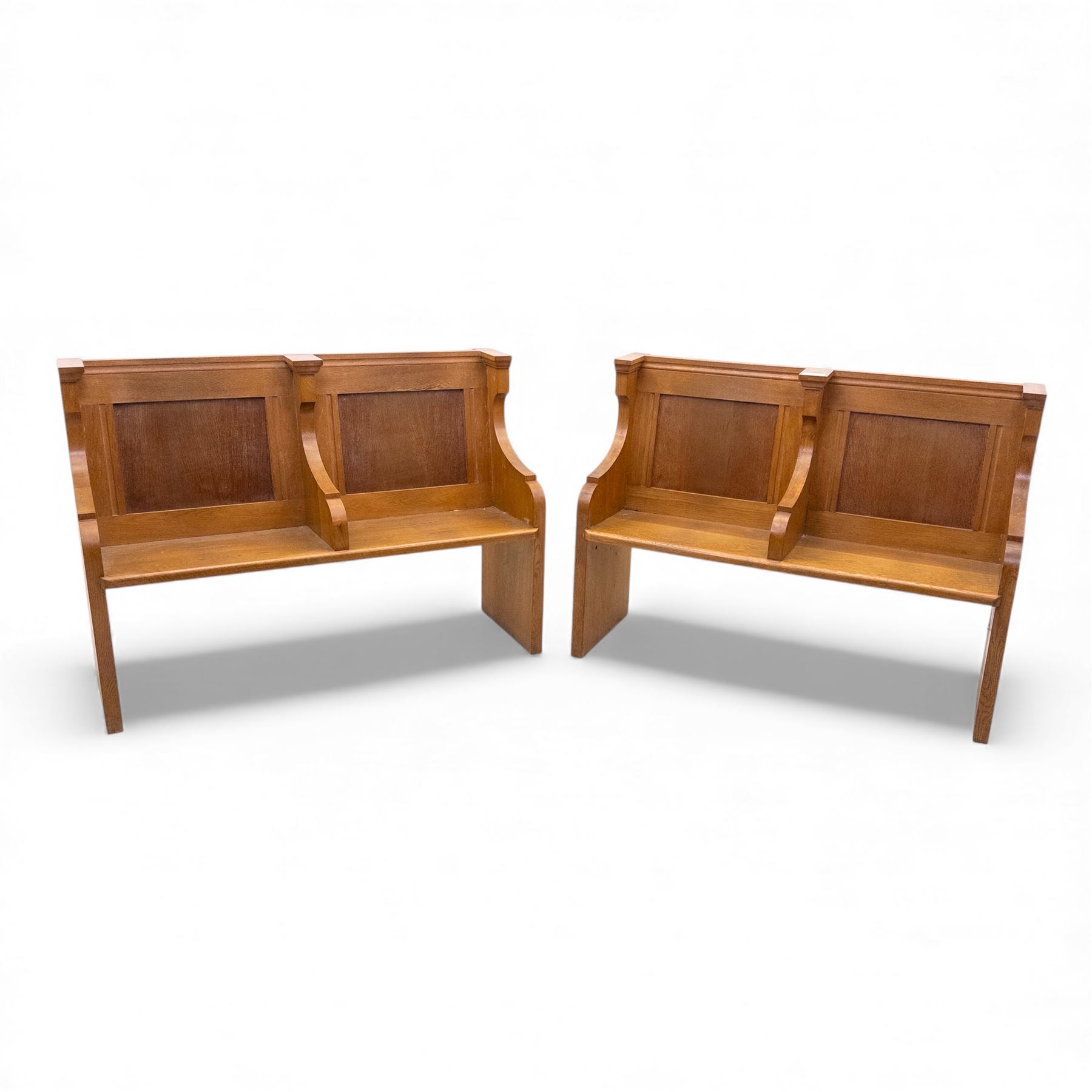 Pair of mid 20th century oak ecclesiastical pews, each with panelled backrests and shaped end supports, of solid construction and mellow honeyed tone