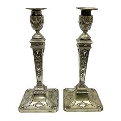 Pair of late Victorian silver plated Adam style candlesticks, each with square base with canted corners and beaded edge, repousse decorated with urns an stiff leaves, leading to a tapering column decorated with rams heads, husk swags, and garlands, supporting a urn shaped sconce with conforming decoration and removable nozzle with beaded edge, H31.5cm