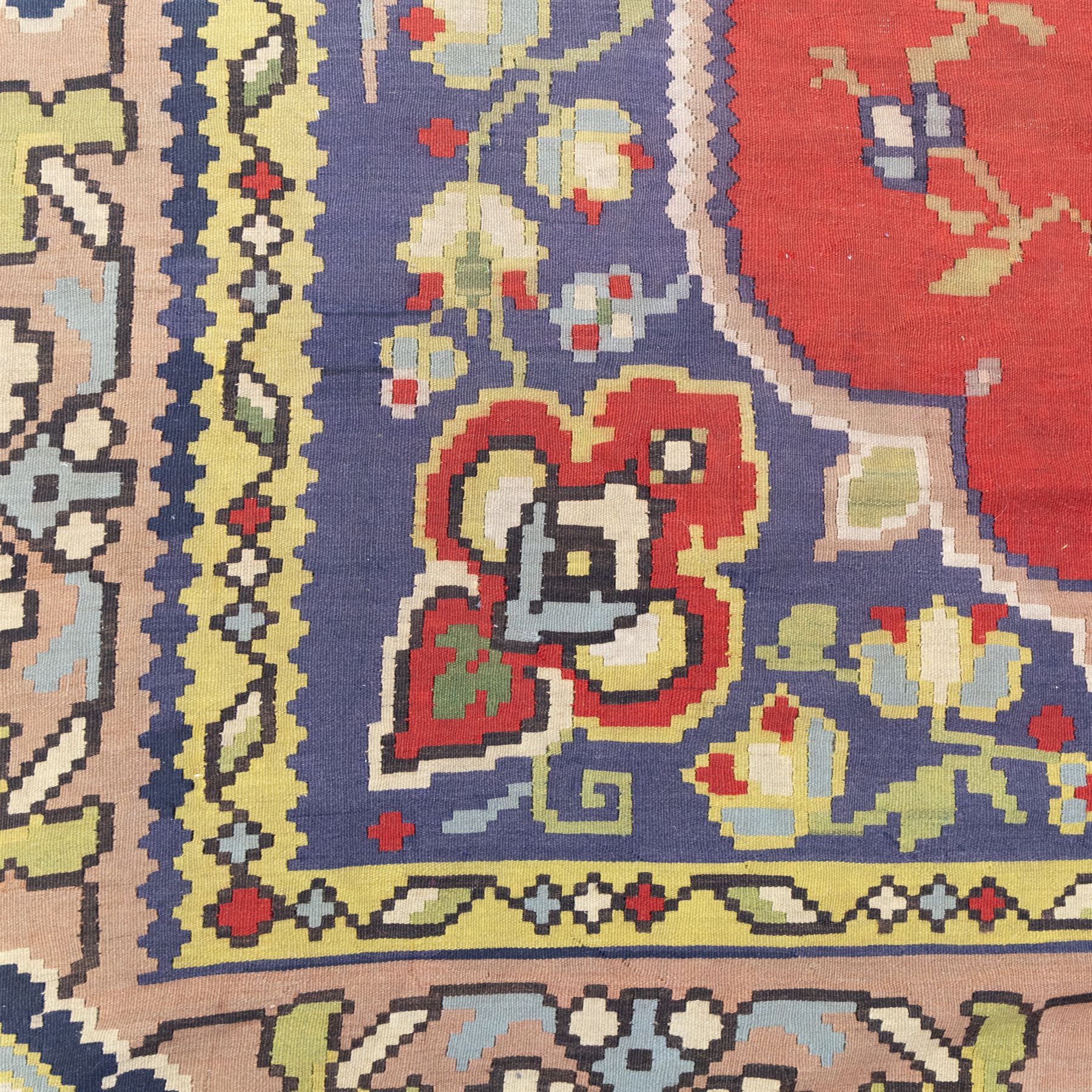 Turkish Malatya type flatwoven rug, decorated with a red medallion field, stylised floral motifs and blue corner panels, enclosed by beige foliate border and outer floral guard band