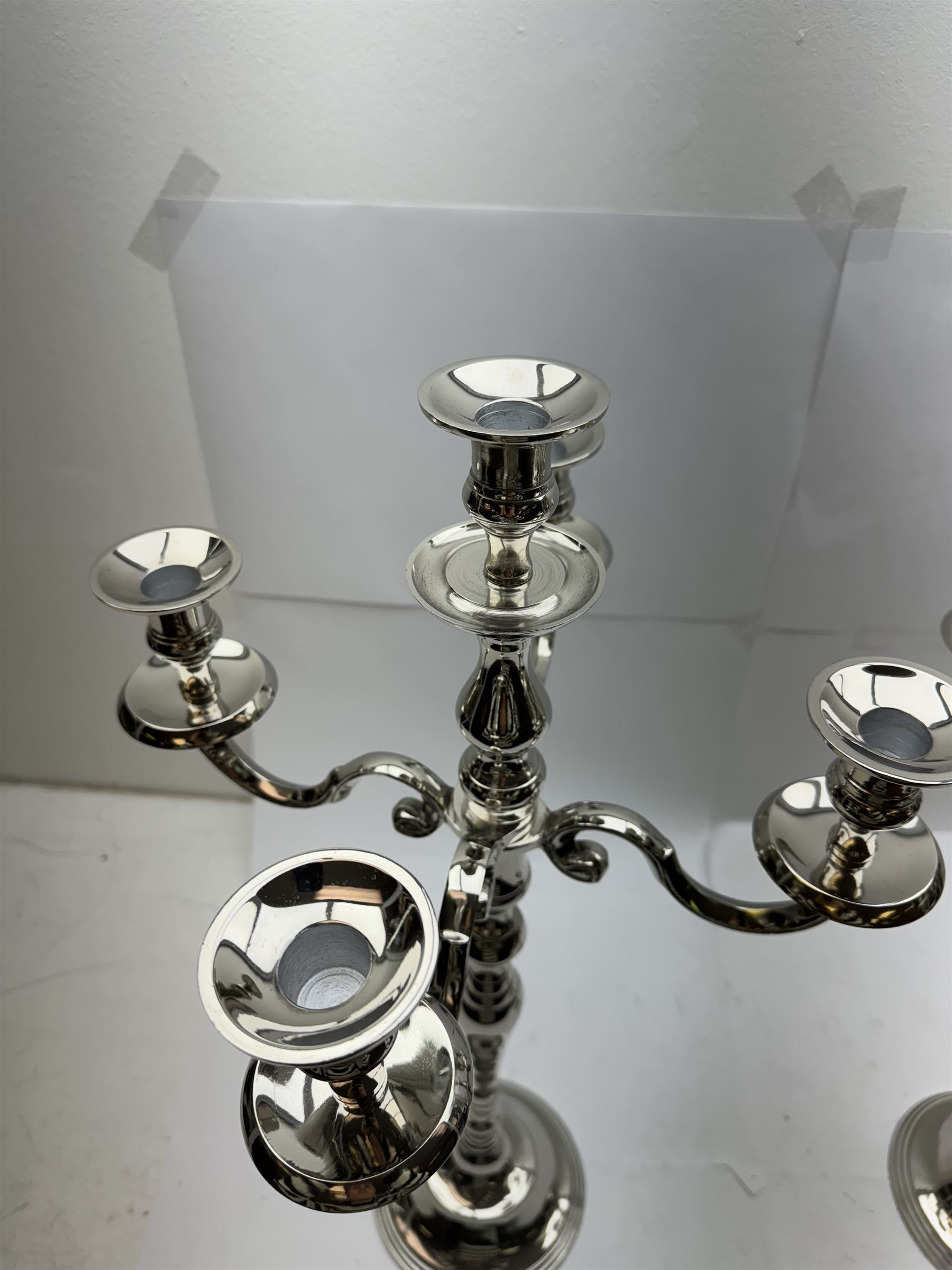 Pair of four branch candelabras, urn-shaped nozzles raised upon scroll branches supported from tapering central stem, with a stepped circular base, H59cm