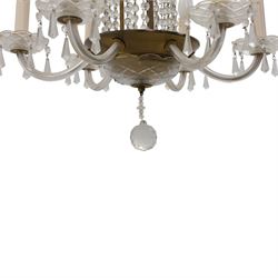 Early 20th century Continental glass and brass six branch chandelier, the central baluster column hung with graduated faceted glass drops, issuing six scrolling glass arms each fitted with candle sconces and drip pans, suspended from a fluted glass canopy
