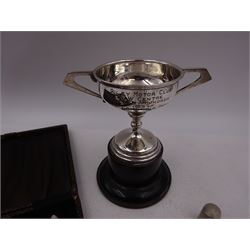 Group of silver, comprising 1930s silver trophy, with angular twin handles and engraved body, upon ebonised wooden base, silver mounted cheroot holder, thimble, 'The Classic' lighter, a cased set of coffee spoons, and a vesta case, all hallmarked with various dates and makers, trophy H11.5cm