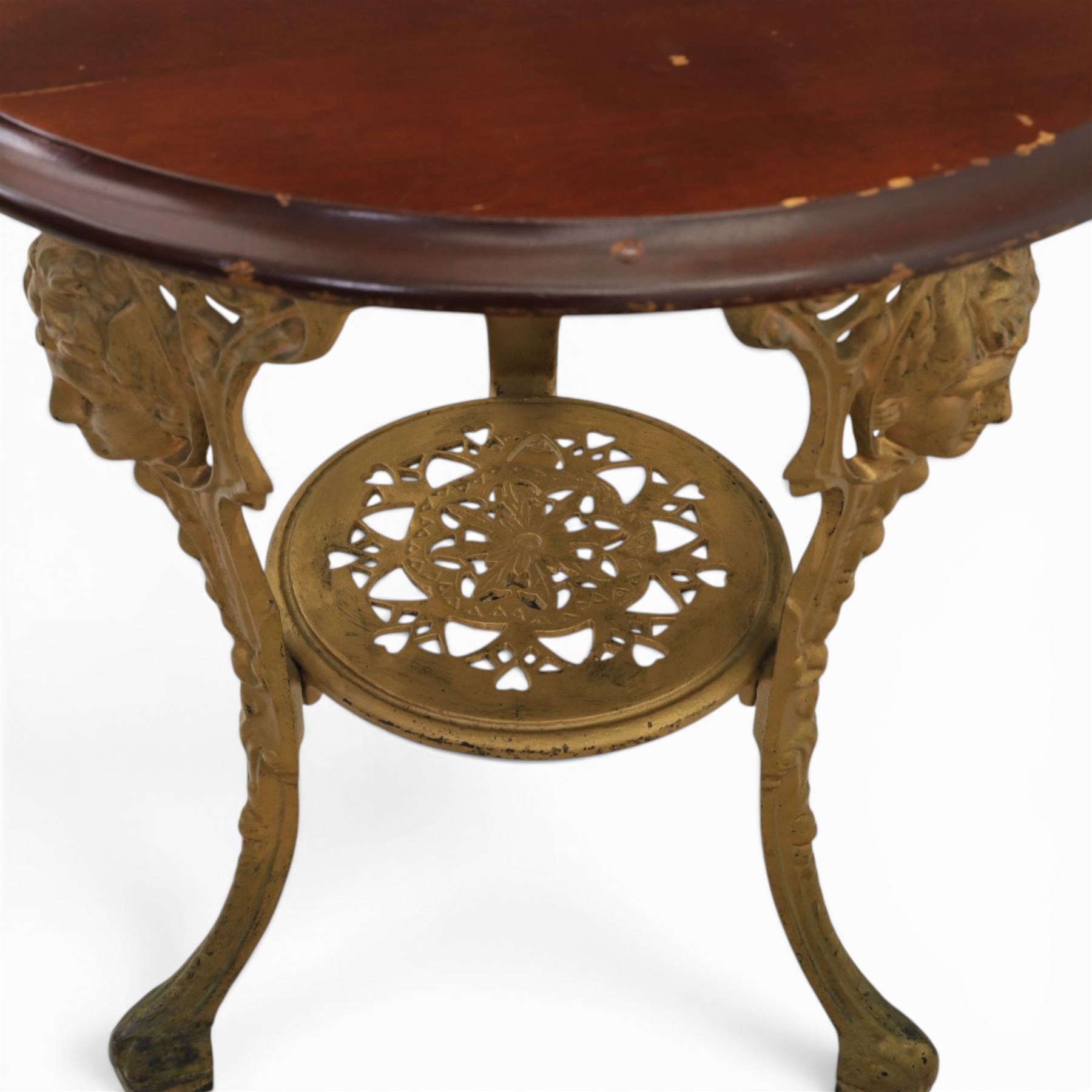 Britannia style cast iron pub table and pair of stools, moulded circular top raised on a gilt painted frame, featuring masks and acanthus detailing united by an under tier, the stools with red floral design (Stools diameter 34cm, height 47cm) 