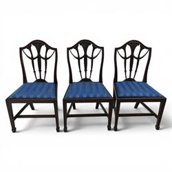 Set of eight George III style mahogany dining chairs, comprising two carvers and six singles, each with shaped top rail above pierced splay carved with feathers, with drop in stuffover seats upholstered in blue striped fabric, raised upon square tapering legs joined by stretchers, together with a mahogany twin pedestal dining table, the oval top with central leaf raised upon turned columns and splayed reeded legs terminating in lion paw feet and brass castors, 