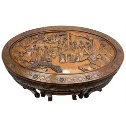 Chinese carved hardwood coffee table with six inset stools or side tables, oval top carved with figures and traditional pagoda scenes, with matching carved frieze, raised on tapering supports with paw feet