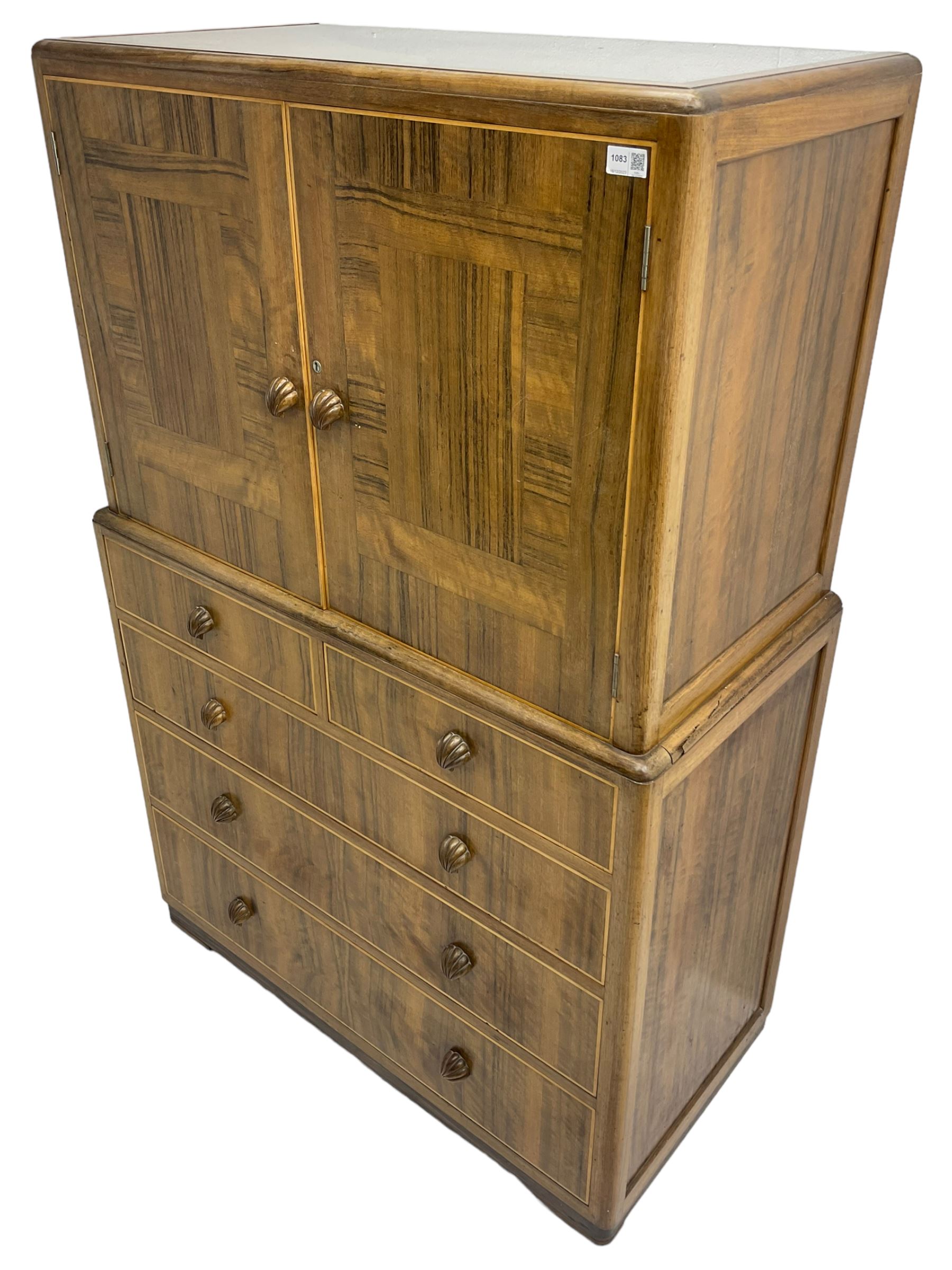 Early 20th century Art Deco walnut cocktail tallboy chest, fitted with double cupboard enclosing two shelves over two short and three long drawers, each with shell shaped handes