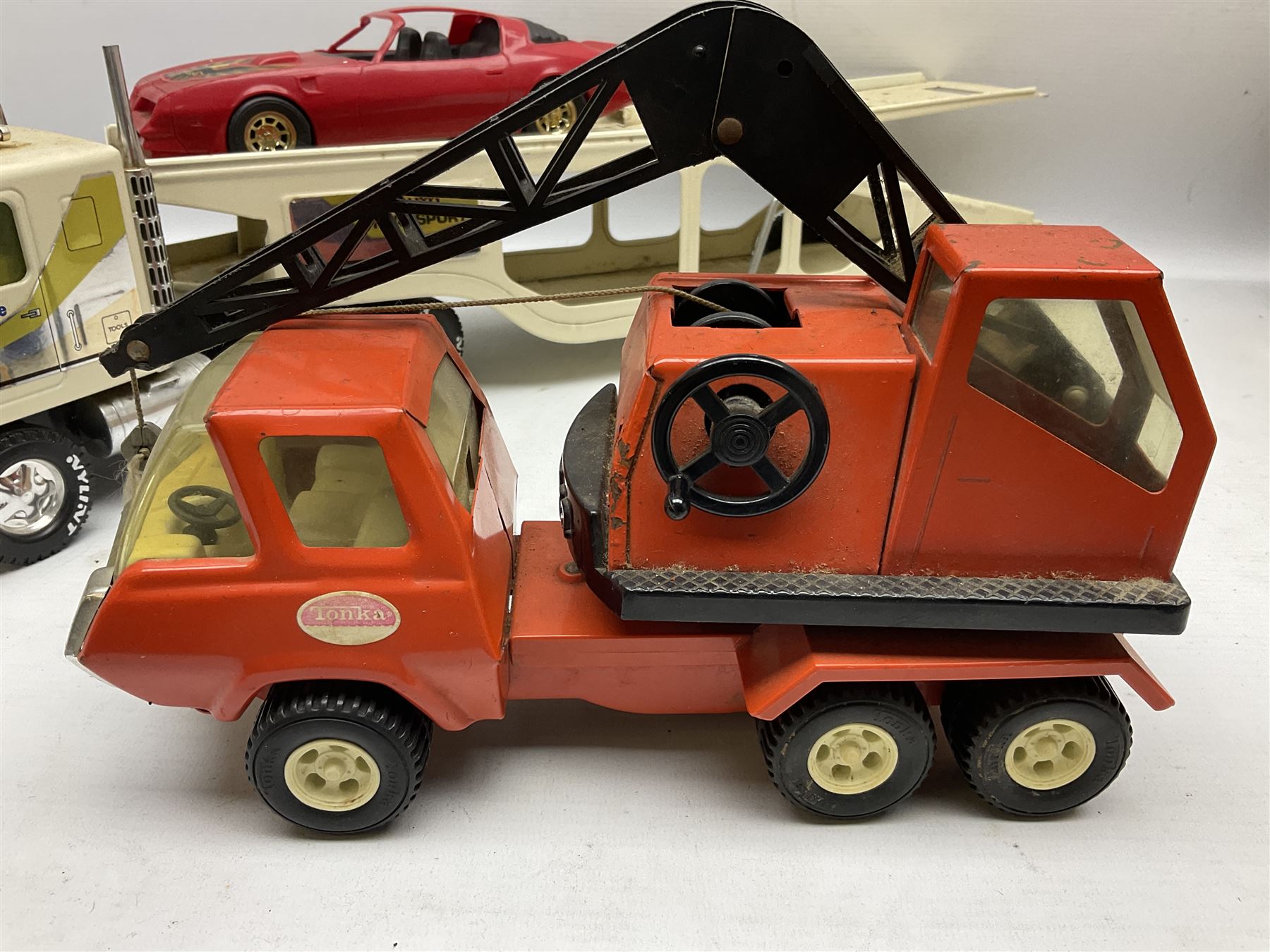 American Nylint large scale tin-plate car transporter L59cm carrying a Testor Toys plastic car; Tonka tin-plate mobile crane; boxed Sarony Cigarettes tin-plate roulette game with rules; and Japanese style tin-plate box, the lid inset with a revolving poker dice game (4)