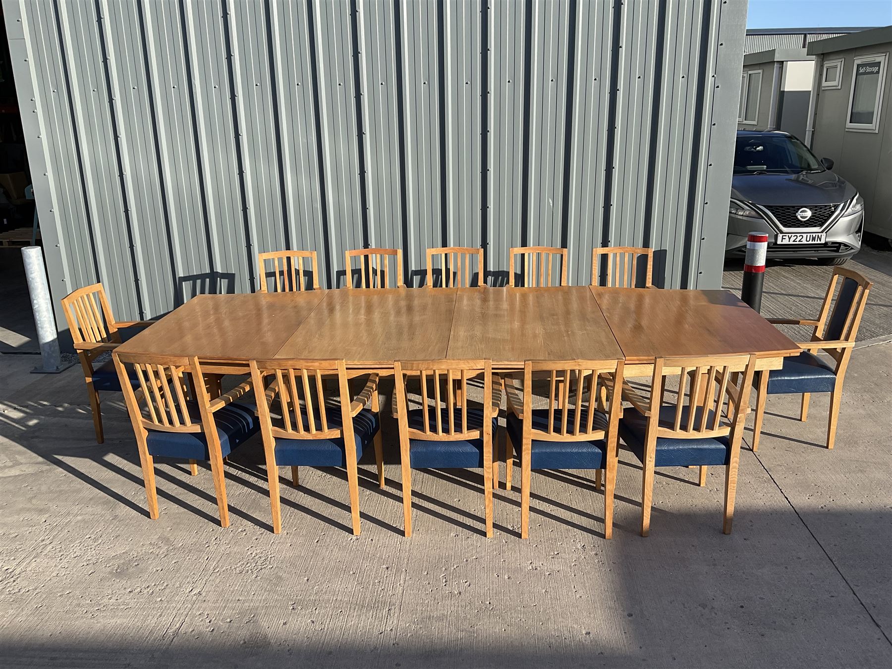 Light oak bespoke boardroom table, concave form, four sectional top on square discreet legs (12' x 5'), with twelve armchairs including 'Chairmans' chair