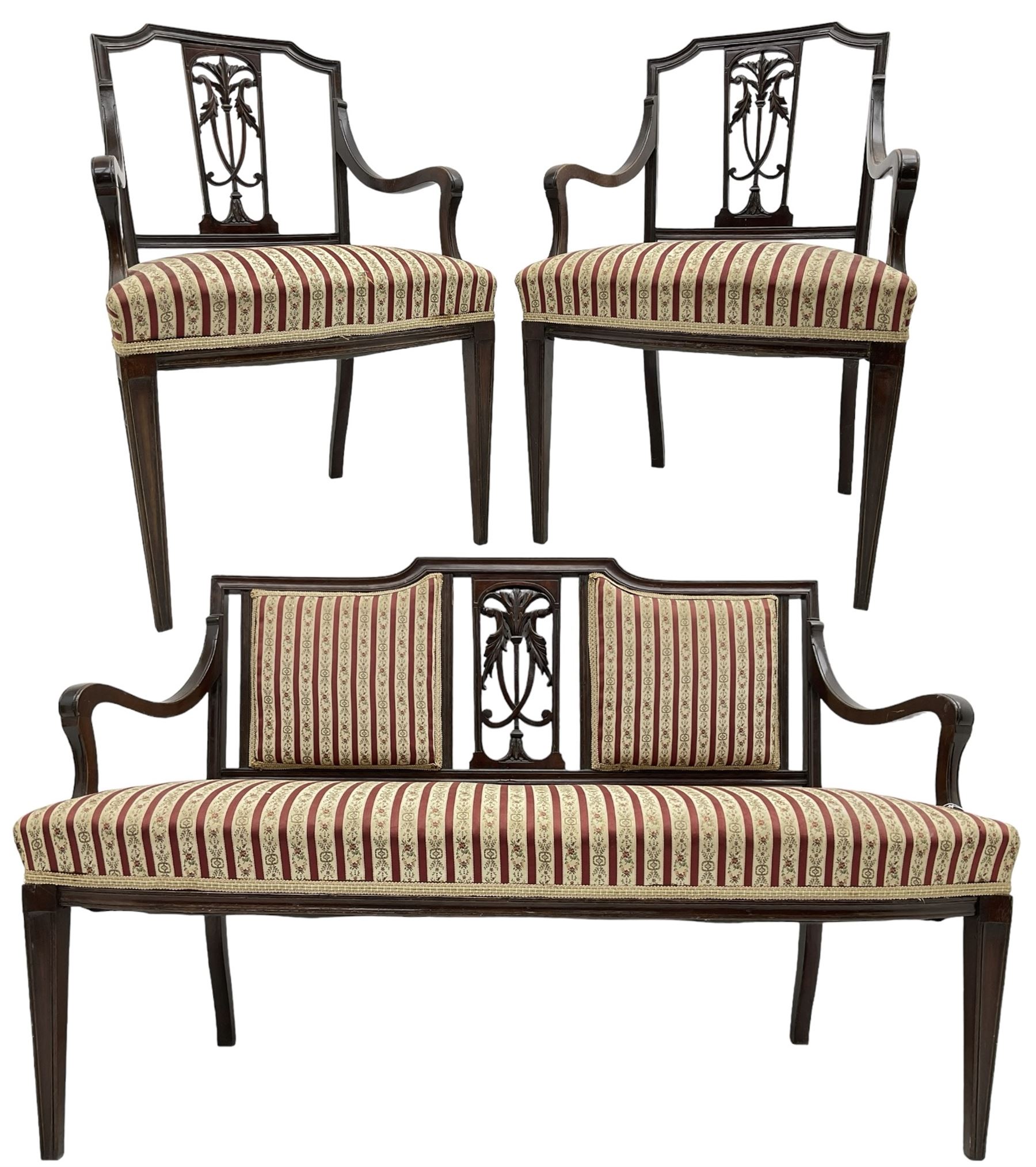 Edwardian mahogany framed three-piece salon suite - two-seat sofa, stepped cresting rail over acanthus and scroll carved pierced splat, upholstered in striped fabric (W124cm, H87cm, D62cm); and a pair of matching armchairs (W60cm) 