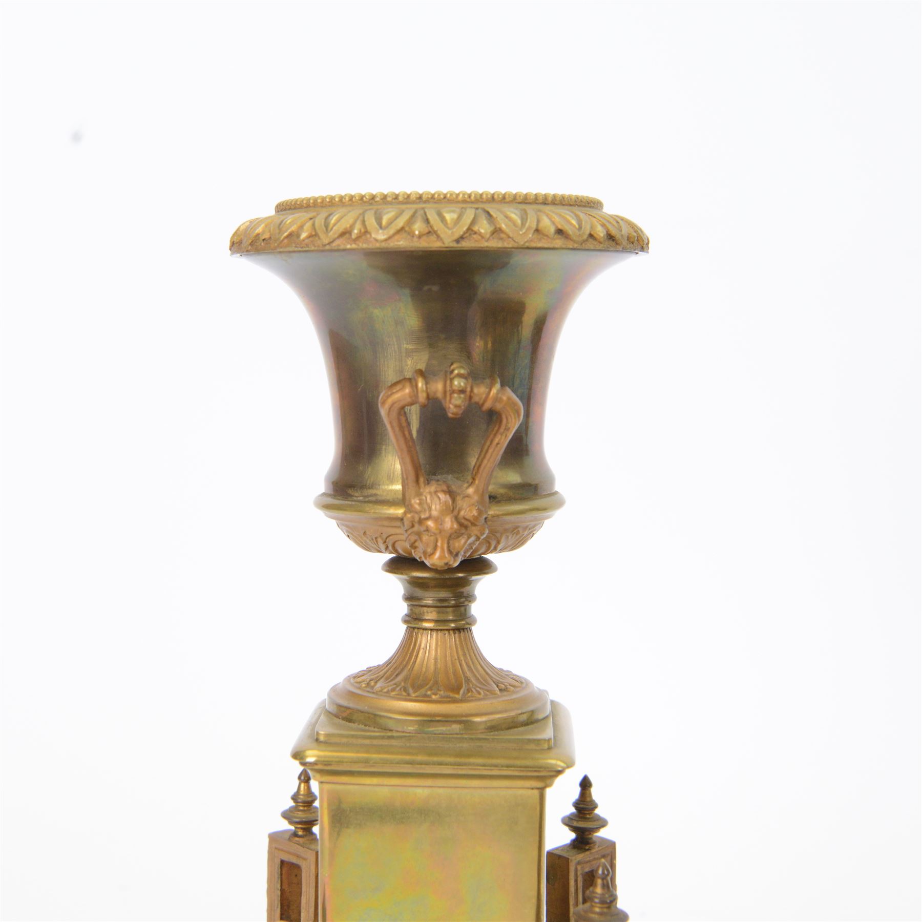 French- Art-deco Edwardian 8-day four-glass clock garniture, with etched glass panels, cast brass decoration to the corners of the case and splayed feet representing cloven hoofs to the base, case surmounted by a large oval urn on a tiered brass platform, two part dial with a recessed brass centre comprising of pierced radial decoration, with steel spade hands and Arabic numerals to the chapter, rack striking movement with a deadbeat Brocot escapement, striking the hours and half-hours on a bell. With a visible twin file mercury pendulum. Garni comprising two large twin handled urns on rectangular pedestals raised on conforming feet representing cloven hoofs, Clock and garni presented on three shaped wooden gesso bases with velvet pads. With key.