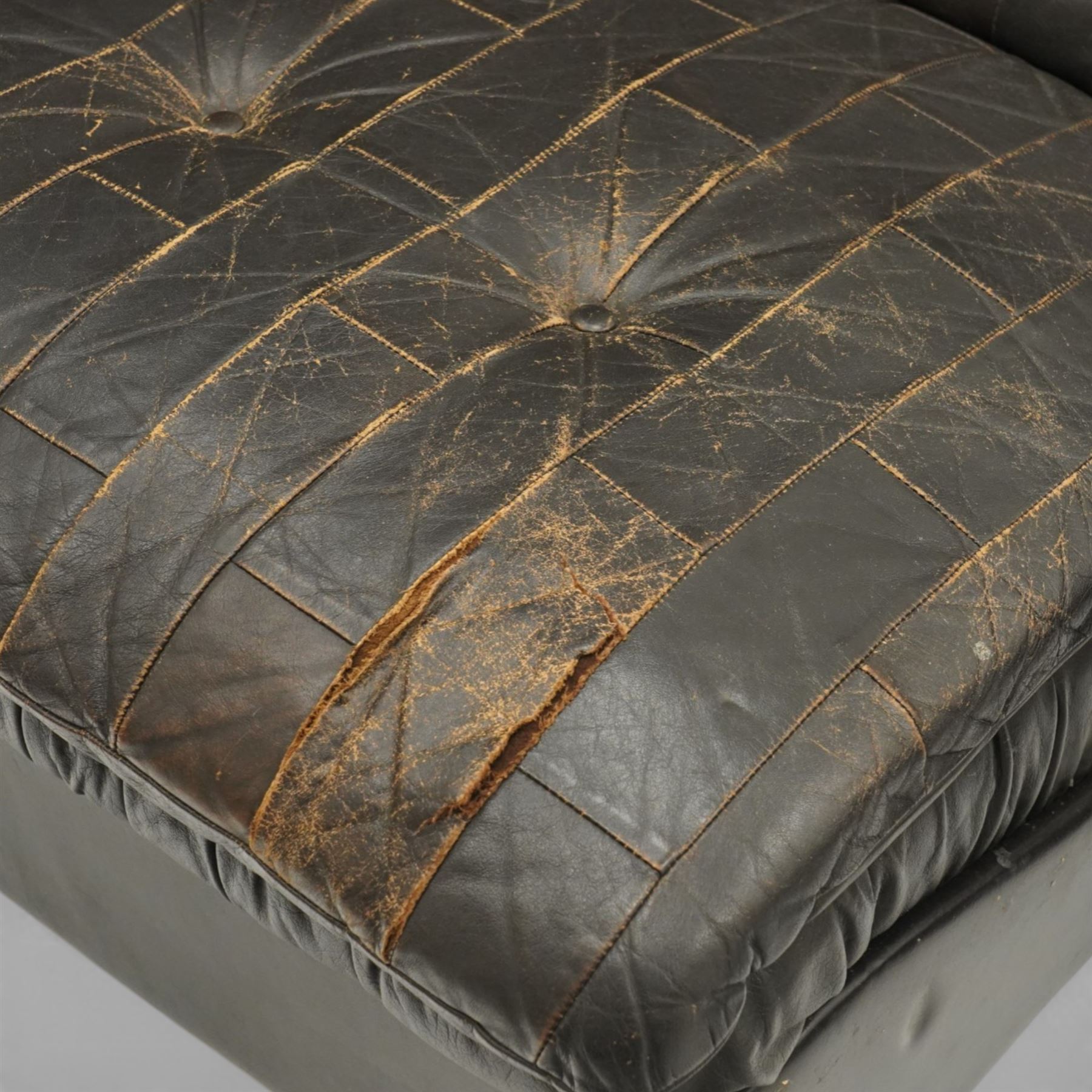 Mid 20th century leather upholstered two-piece sectional sofa with footstool, buttoned back cushions with stitched panel decoration, padded armrests and deep seat cushions, raised on concealed supports