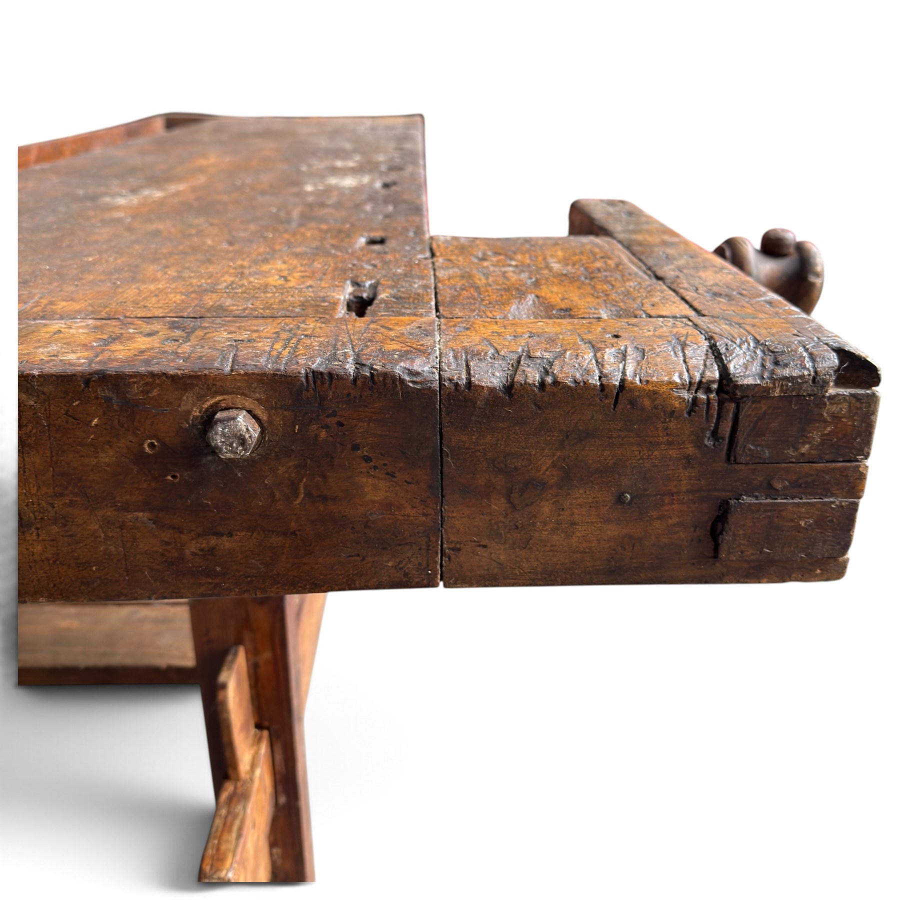 Large early 20th century rustic stained reclaimed pine workbench, the substantial plank top with recessed tool well and two homemade wooden screw vices, above a single frieze drawer and slatted undertier, raised on trestle end supports