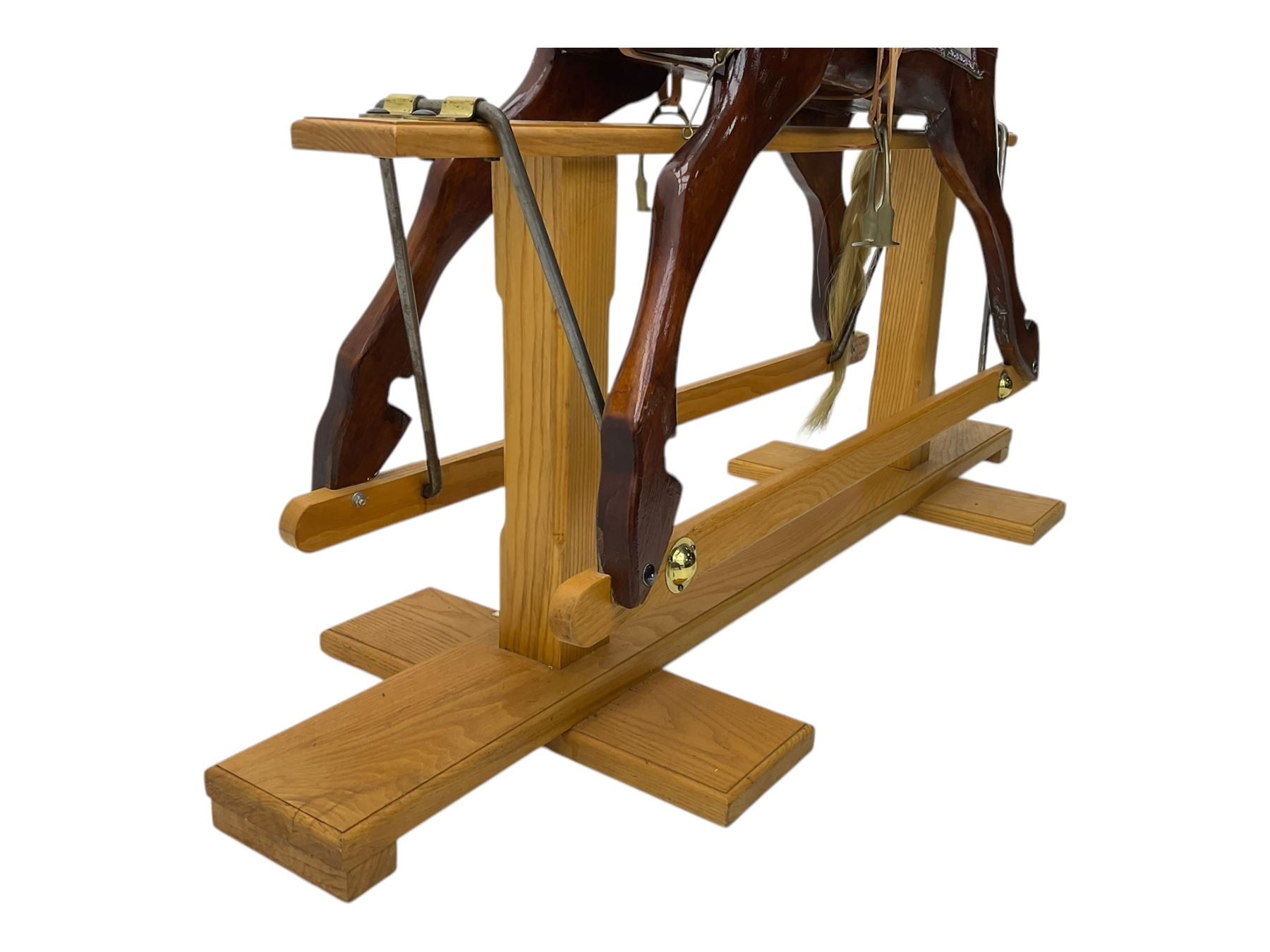 Contemporary carved wooden rocking horse, with leather saddle and bridle, horsehair mane and tail, raised on a pine stand with swing iron supports