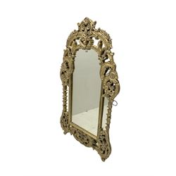 Large pale gilt finish ornate wall mirror, in scrolled foliate frame decorated with flower heads, plain mirror plate