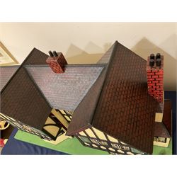 Large Tri-ang No.93 doll`s house in the 'Stockbroker's Range' c1935; two-storey double-fronted Tudor design, half timbered gables, two-storey bay windows, cream and mock shrubbery to front, opening metal framed windows with green shutters, red simulated tiled roof with chimney, integral garage with opening doors, front elevation has four hinged doors opening to reveal two bedrooms with fire places, living room, bathroom and kitchen with built in dresser and sink, entrance hall and staircase, side entrance with porch and seat and sun dial over on chimney stack; some wiring for electrical lighting; metal Tri-ang Toys disc verso; comprehensively furnished H66cm L117cm D43cm