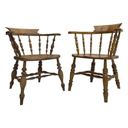 Late 19th century elm smoker’s bow armchair, curved top rails over turned spindle backs, shaped seats, raised on turned legs united by turned stretchers; together with a similar smoker’s bow armchair (2)