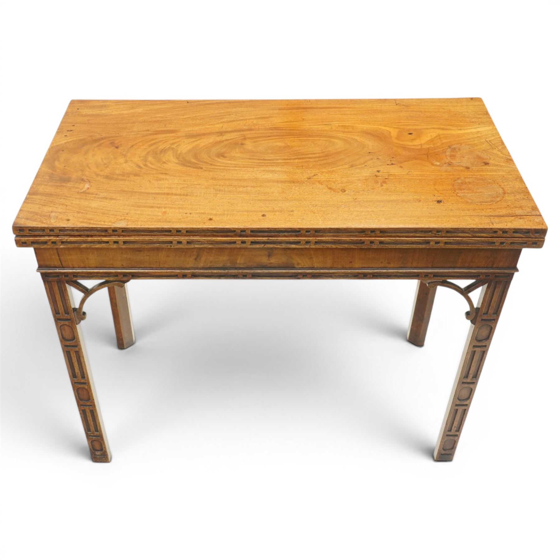 George III Chippendale design mahogany table, the rectangular hinged top with geometric carved edge, opening to reveal a baize-lined interior supported by twin concertina rear gateleg supports, over a banded frieze and pierced C-scroll spandrels, the inner chamfered square supports carved with geometric blind-fretwork detail