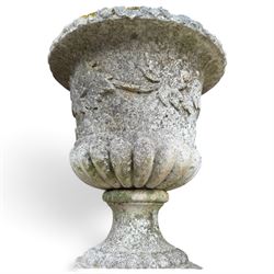 Set of four weathered composite stone urns of campana form, the everted leaf-moulded rolled rim over a body decorated with scrolling fruiting grapevines in relief, over a gadrooned underbelly and waisted socle, lobed collar on square base