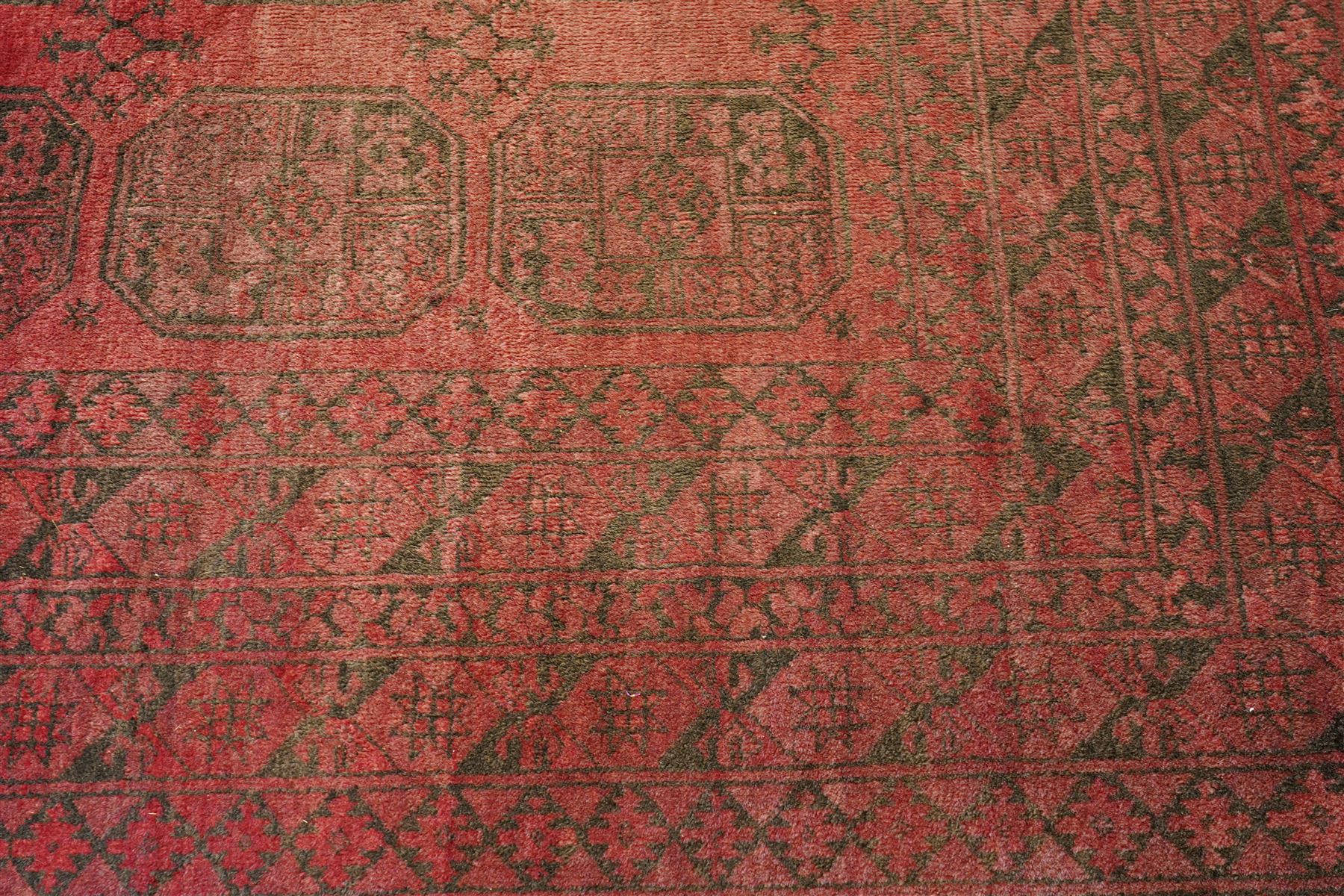 Afghan crimson ground Bokhara rug, the field with three rows of repeating Gul motifs, within six concentric guard bands decorated with repeating geometric patterns