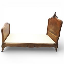 Early 20th century French walnut single bedstead, the shaped and moulded headboard with carved foliate crest above a panelled field, with conforming serpentine footboard with moulded reserves, the shaped apron with applied carved detail, raised upon cabriole supports with carved knees