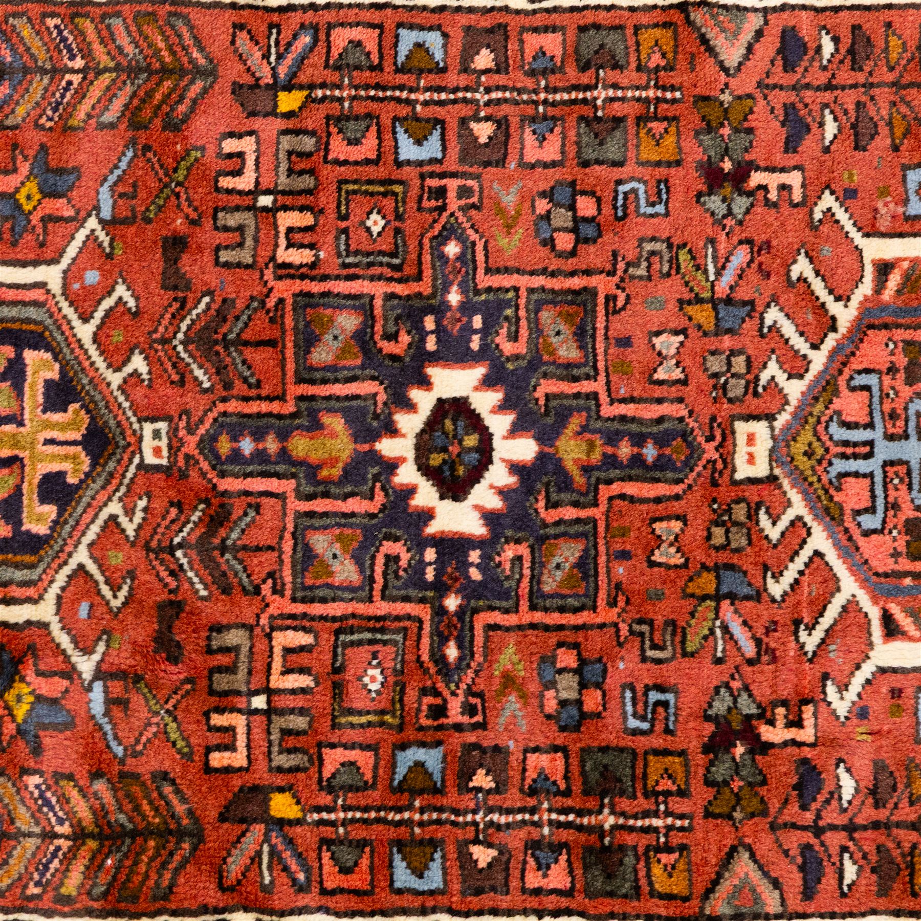 North West Persian Heriz hand-knotted runner, terracotta field decorated with a series of large angular medallions with stylized geometric motifs, surrounded stepped devices, and stylized trees within narrow geometric border, and polychromed edge, cotton fringe ends 