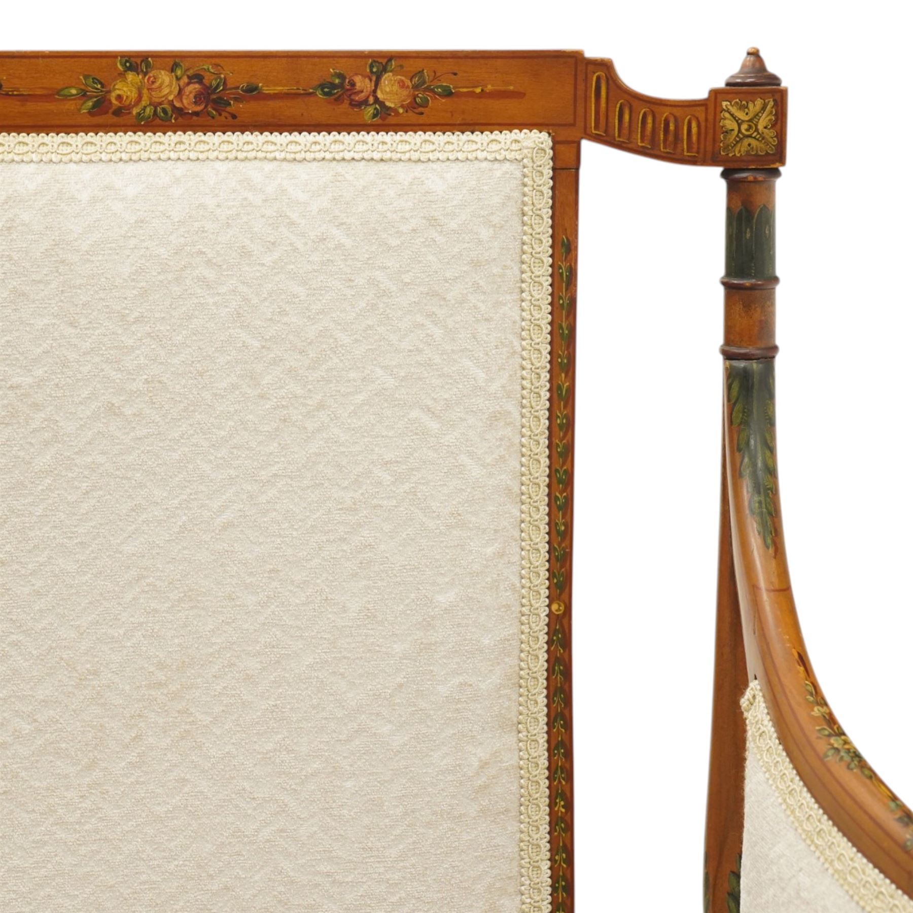 Pair of Victorian Sheraton Revival painted satinwood armchairs, the cresting rail painted with trailing floral bouquets flanked by illusion arcade motifs, over a cameo back and sides with acanthus painted swell-turned uprights, the lower back rail decorated with a bird scene and flanking pierced foliate design, upholstered in ivory fabric, raised on turned supports with further acanthus leaf paintwork, terminating to brass castors