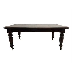 Edwardian oak extending dining table, rectangular moulded top with canted corners, three additional leaves and winder, flower head carved and turned supports with fluted decoration, on brass and ceramic castors