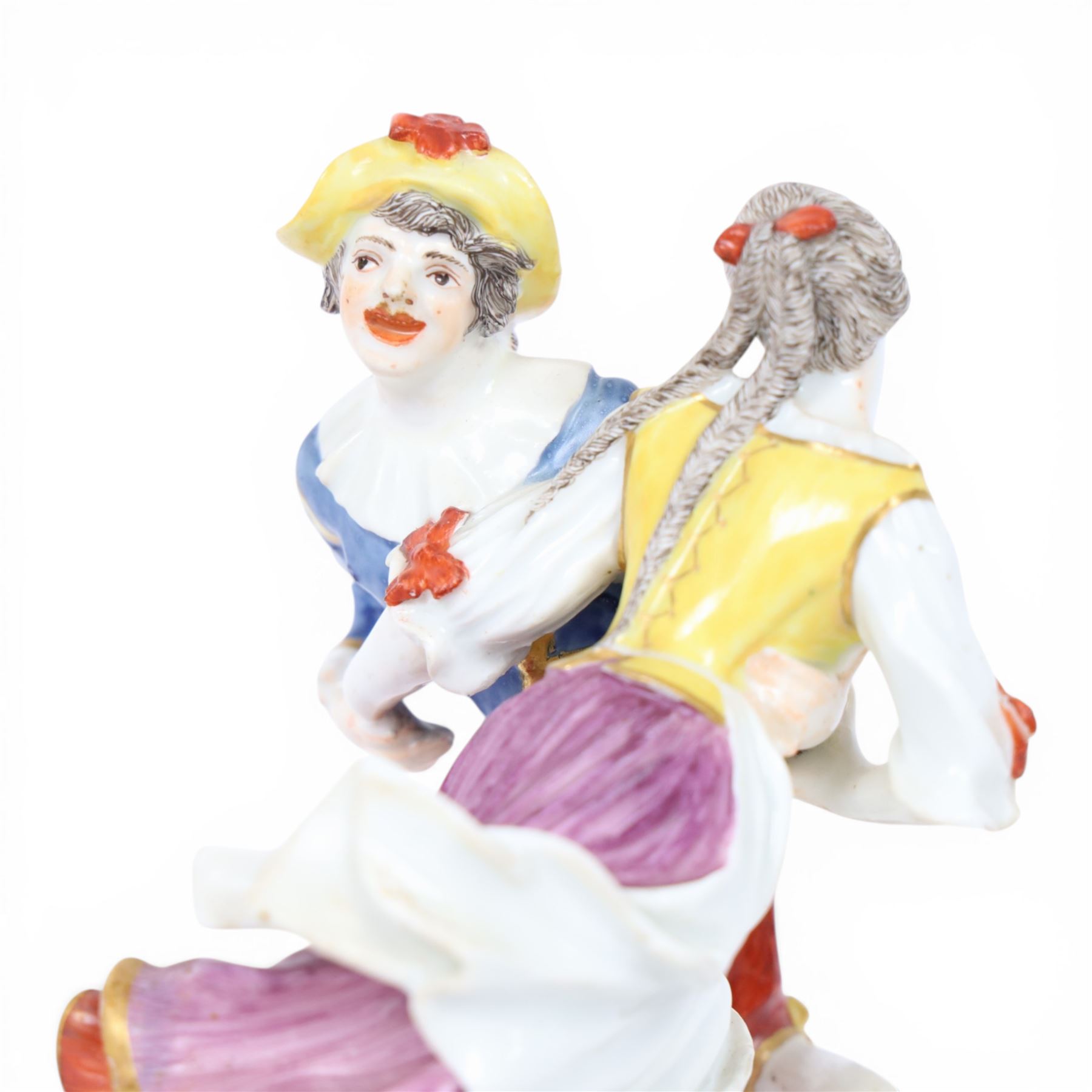 Mid 18th century Meissen figure group, The Tyrolean Dancers, circa 1740, modelled as two swirling figures with their arms linked, he in yellow hat with red rosette, blue jacket, red breeches with red rosette, and yellow shoes with green rosette, she in white blouse with red ribbons, yellow and red bodice, white apron over puce skirt and yellow shoes with green rosettes, her hair fashioned into two plaits secured by red ribbon, upon a shaped mound base, within a scrolling gilt metal mount, with blue crossed swords mark to base, overall H19cm
