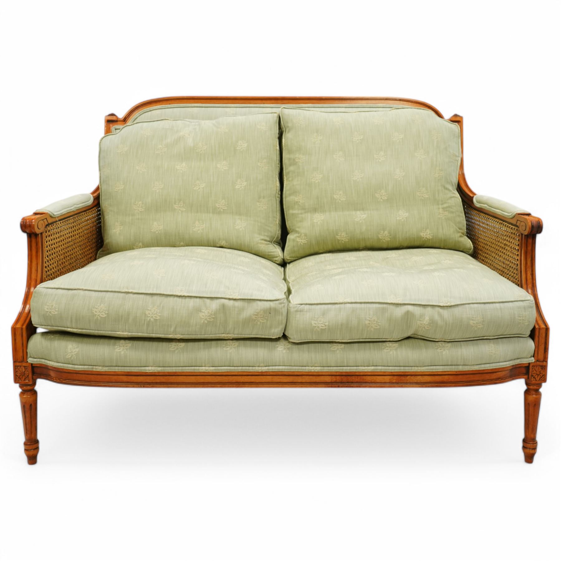 French Empire design varnished wood three piece lounge suite comprising of two cane armchairs and matching sofa, carved top rails with foliate terminals, cane side panels and padded scroll arms, upholstered in a green brocade with matching piping, on fluted legs
