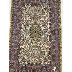 Central Persian Kirman ivory ground rug, decorated all-over with flower heads and trailing foliage, shaped pink and blue ground borders with olive green outer band