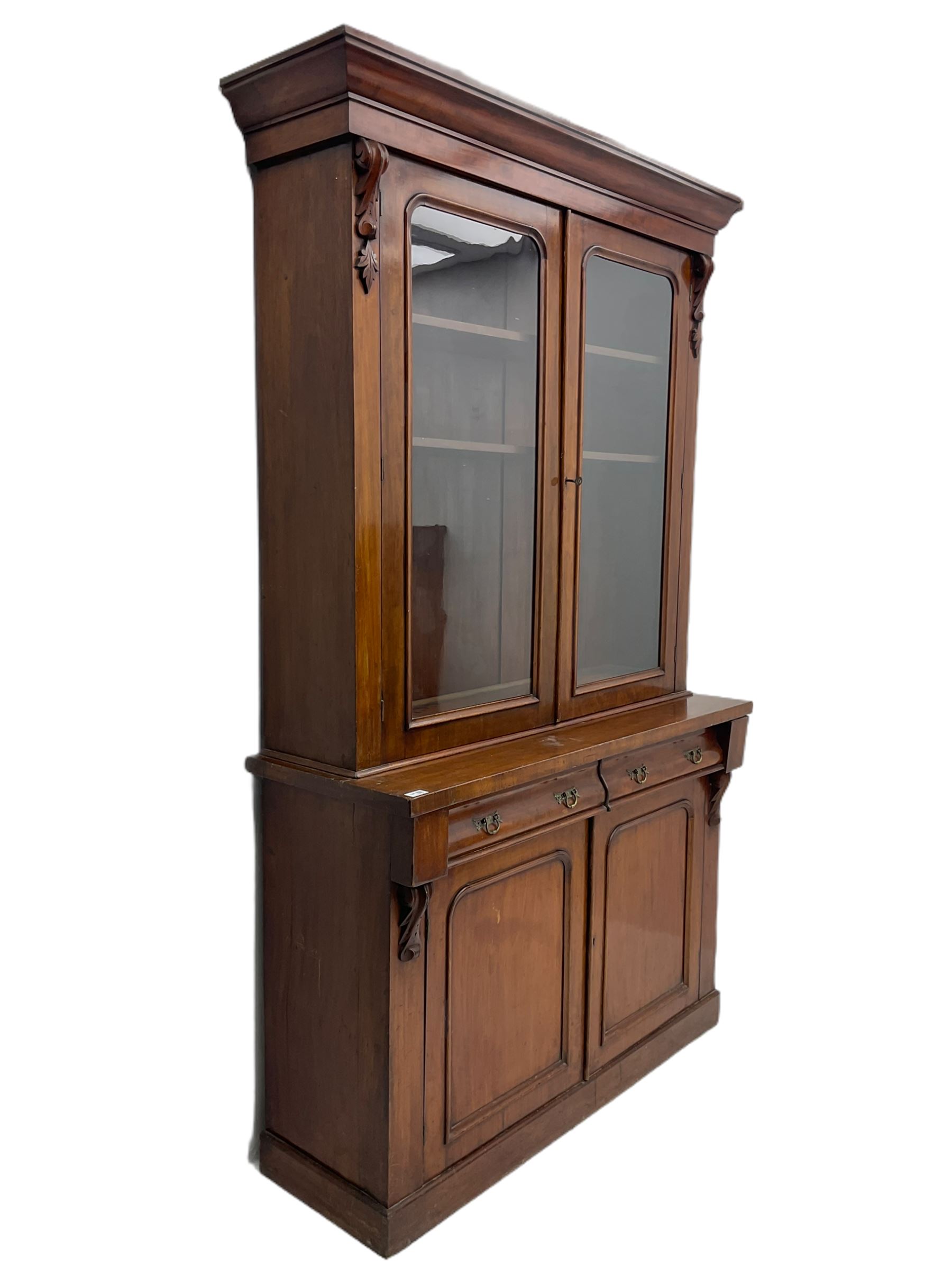 Victorian mahogany bookcase on cupboard, projecting cornice over two glazed doors and carved corbels, fitted with two drawers and double cupboard, plinth base