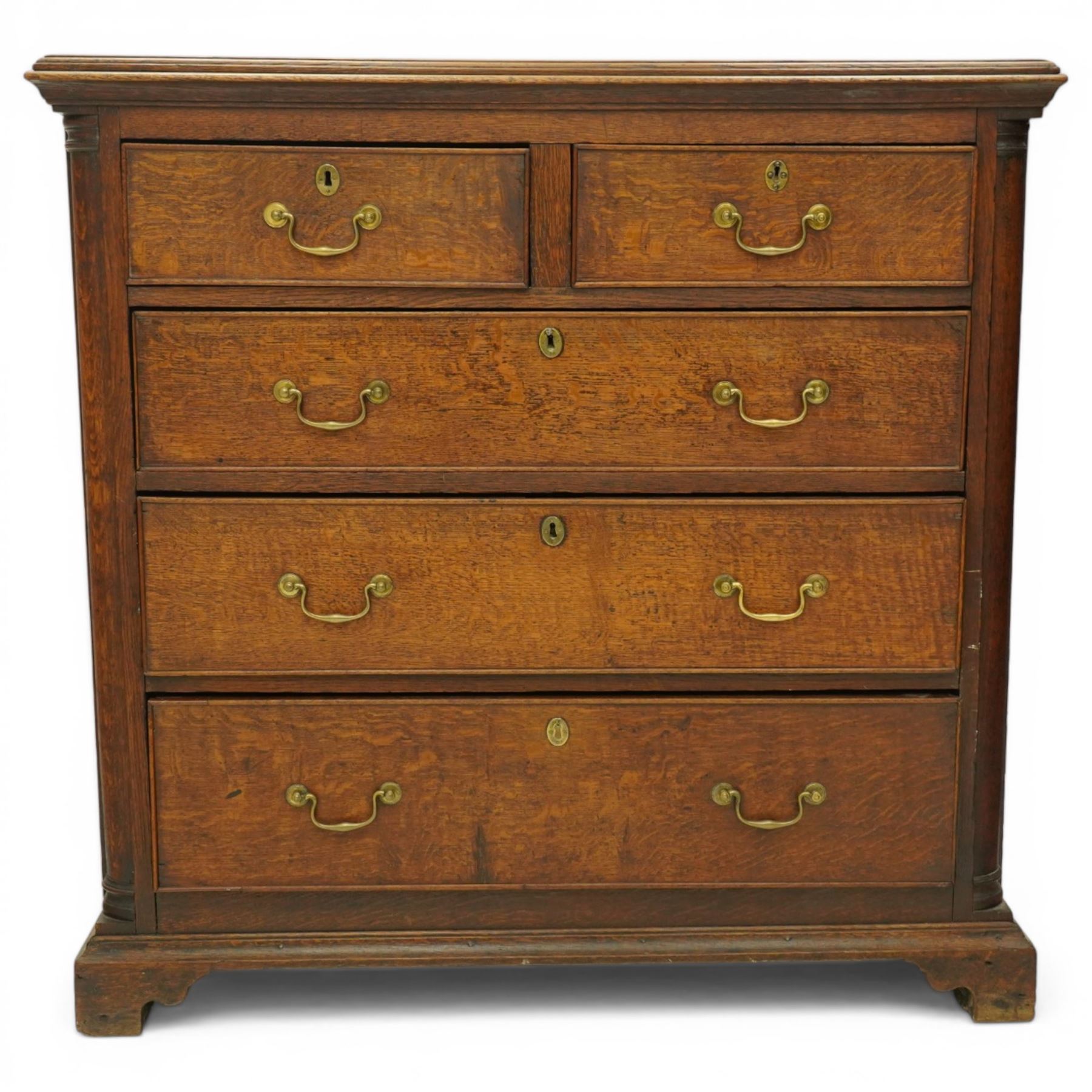 Georgian oak chest of drawers, fitted with two short over three long drawers, with brass swing handles and escutcheons, flanked by quarter turned pilasters, raised on shaped bracket feet