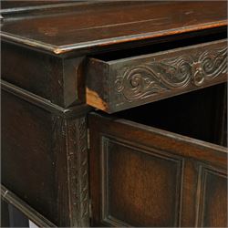 Early 20th century carved oak sideboard Jacobean style with panel back on cup and cover legs, the top section with carved panels and reeded moulding, three deep frieze drawers over triple panelled cupboard doors, raised on carved baluster legs joined by lower shelf
