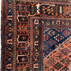 Joshgan Persian wool rug, with diamond-framed medallion, on a deep red field filled with geometric-shaped floral motifs and indigo-filled spandrels 