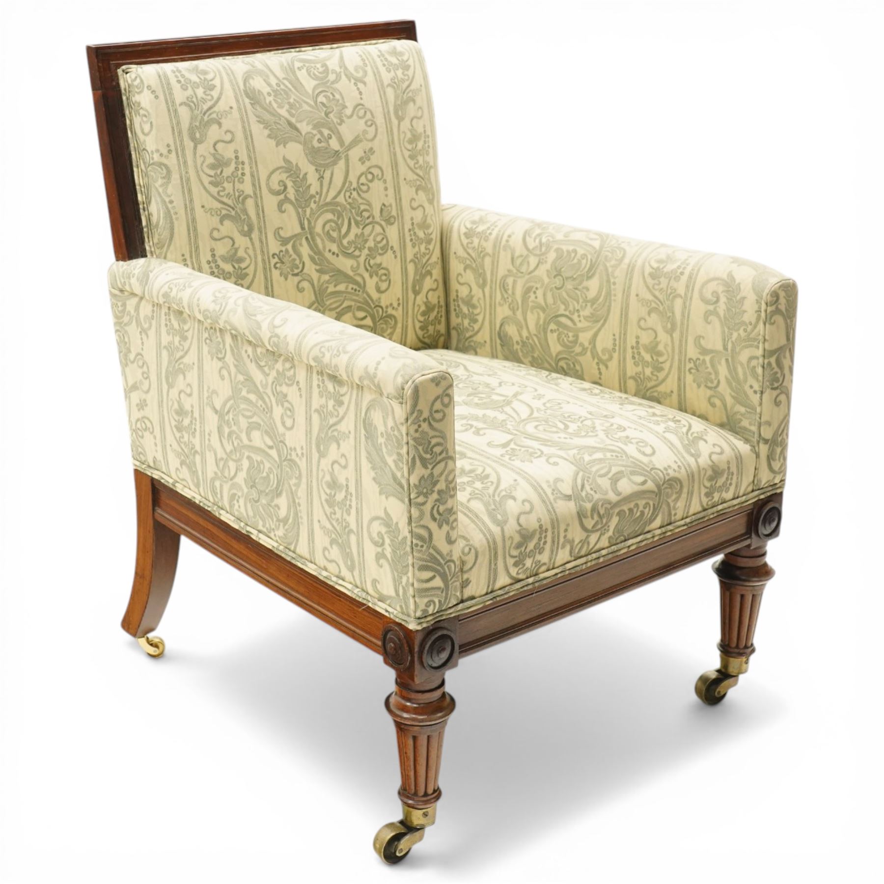 William IV rosewood framed library armchair, squared form with green on ivory ground upholstery, moulded lower seat rail with applied roundels over reeded supports, terminating to brass cups and castors