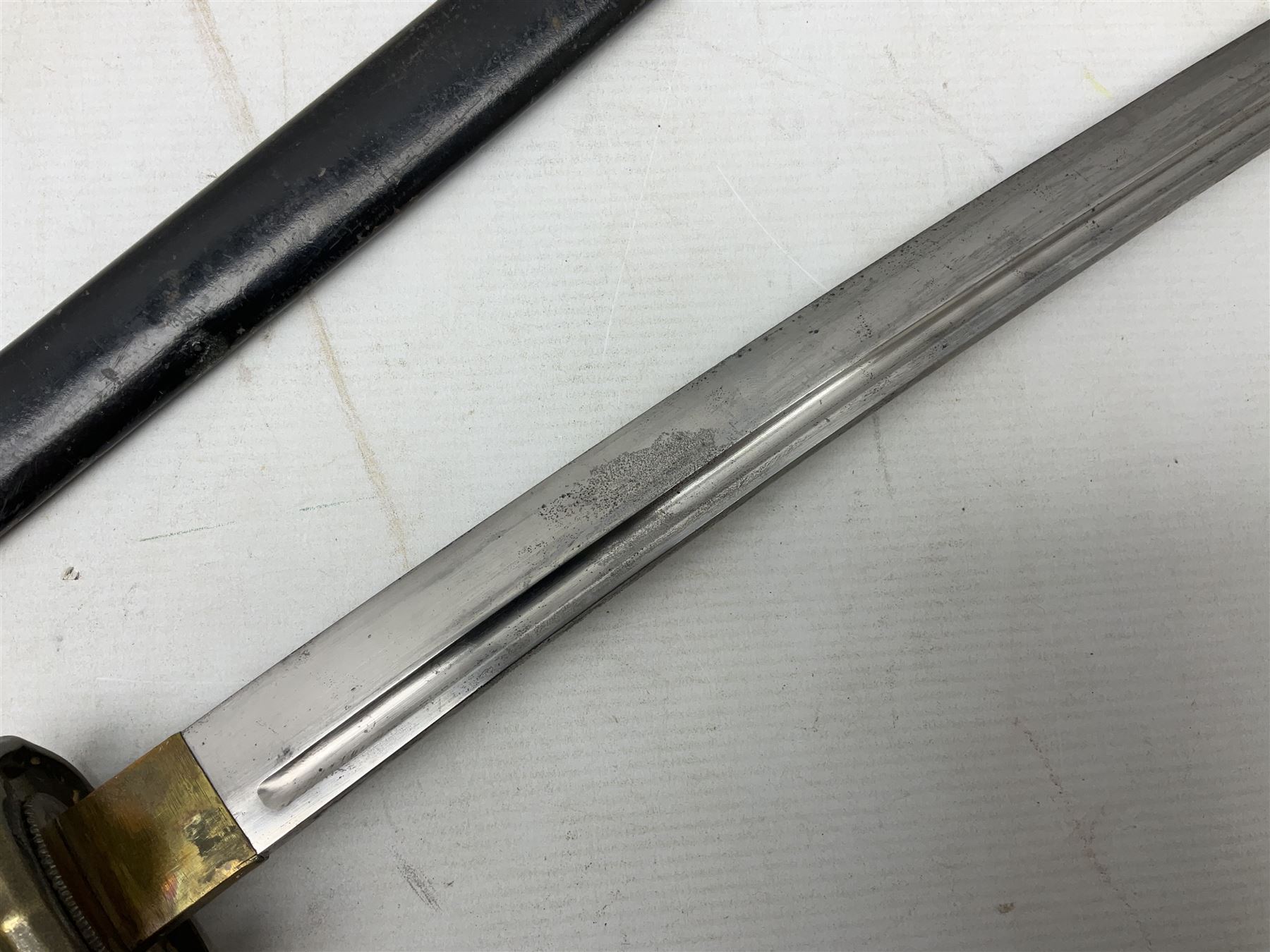 WW2 Japanese Army NCOs sword - katana, the 69.5cm slightly curving fullered blade numbered 14656; arsenal markings stamped near the habaki on the handle; brass tsuba and black painted metal hilt cast to simulate cord bound fish skin; in black painted steel scabbard with single suspension ring L96cm overall