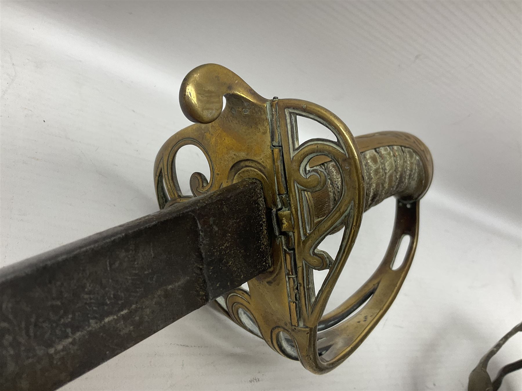 Victorian 1845 pattern infantry officer's sword the 82cm sharpened fullered steel blade with traces of decoration, brass gothic hilt incorporating Victorian cypher, folding back guard, stepped pommel with acanthus leaf backstrap and wire-bound wooden grip with traces of original fish skin covering L96cm overall; together with a reproduction Scottish style basket hilted sword; both lacking scabbard (2)