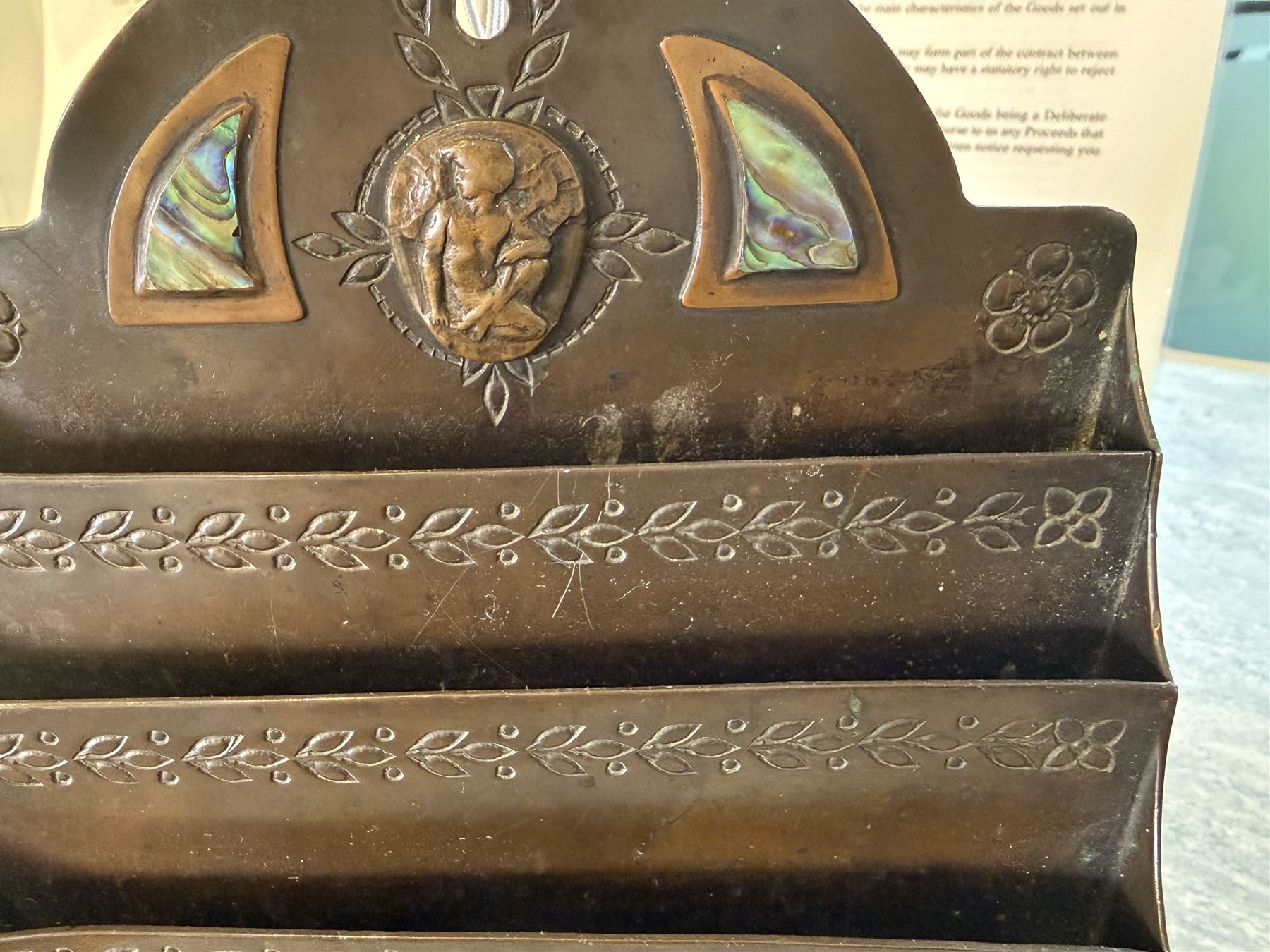 Arts and Crafts bronze letter rack, with three divisions, abalone cartouche to the front, the arch pediment with central figure flanked by abalone and impressed floral decoration, H19cm  