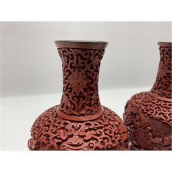 Pair of Chinese cinnabar lacquer vases, each of bulbous baluster form, carved with peonies and foo dogs amongst scrolls, with blue enamel interior and upon wooden bases, H20cm