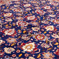 North Central Persian Veramin hand-knotted rug, deep indigo field decorated with an all-over lattice of stylized floral and palmette motifs issuing from an angular vine ornament, enclosed by a broad madder-red border of palmettes and scrolling vine devices between multiple guard stripes, with cotton fringe ends 